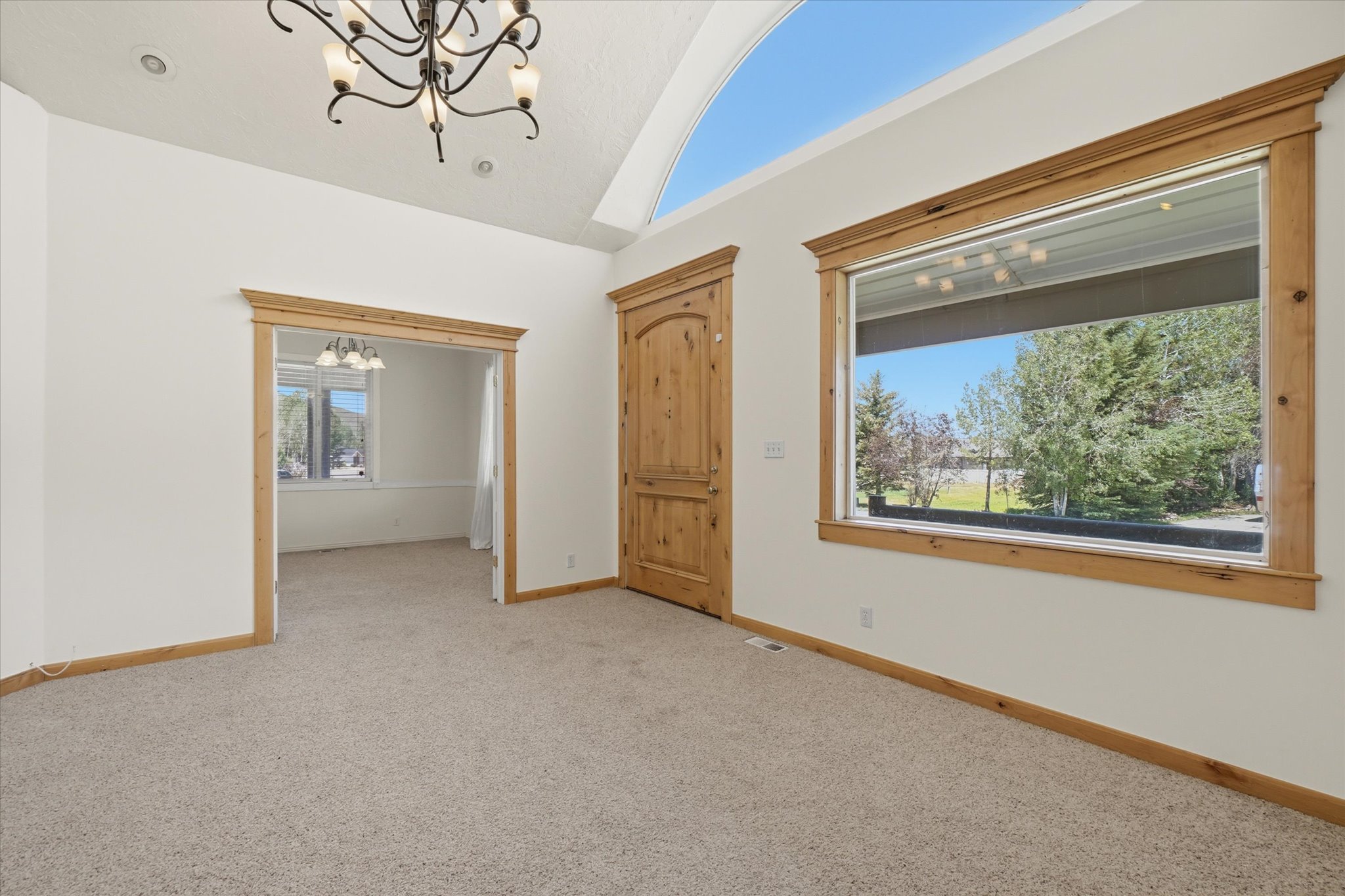 Vaulted ceiling with an arched upper window, complemented by a large rectangular window featuring natural wood trim