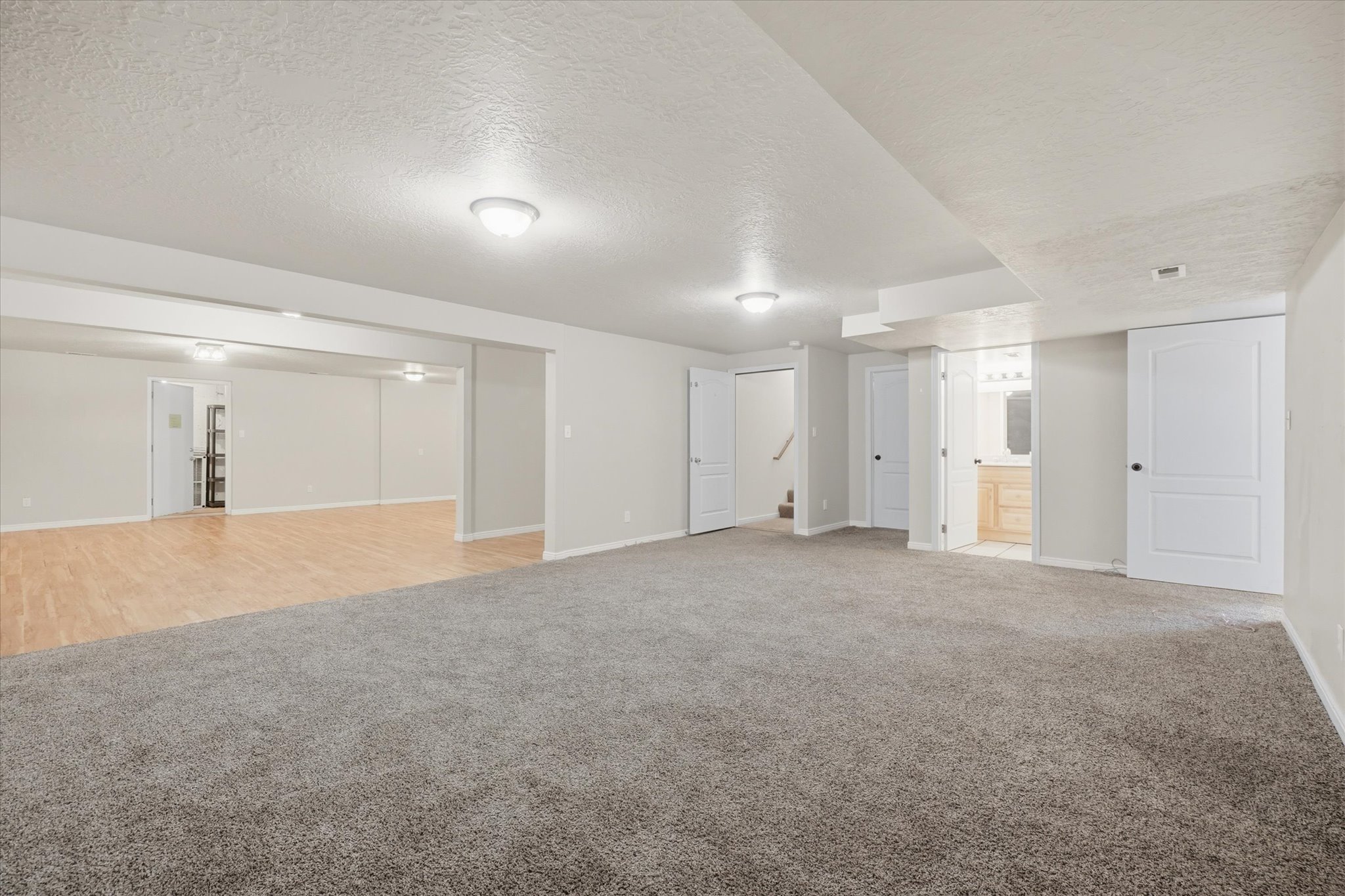 Spacious finished lower level featuring plush carpeting, recessed lighting, and white baseboards