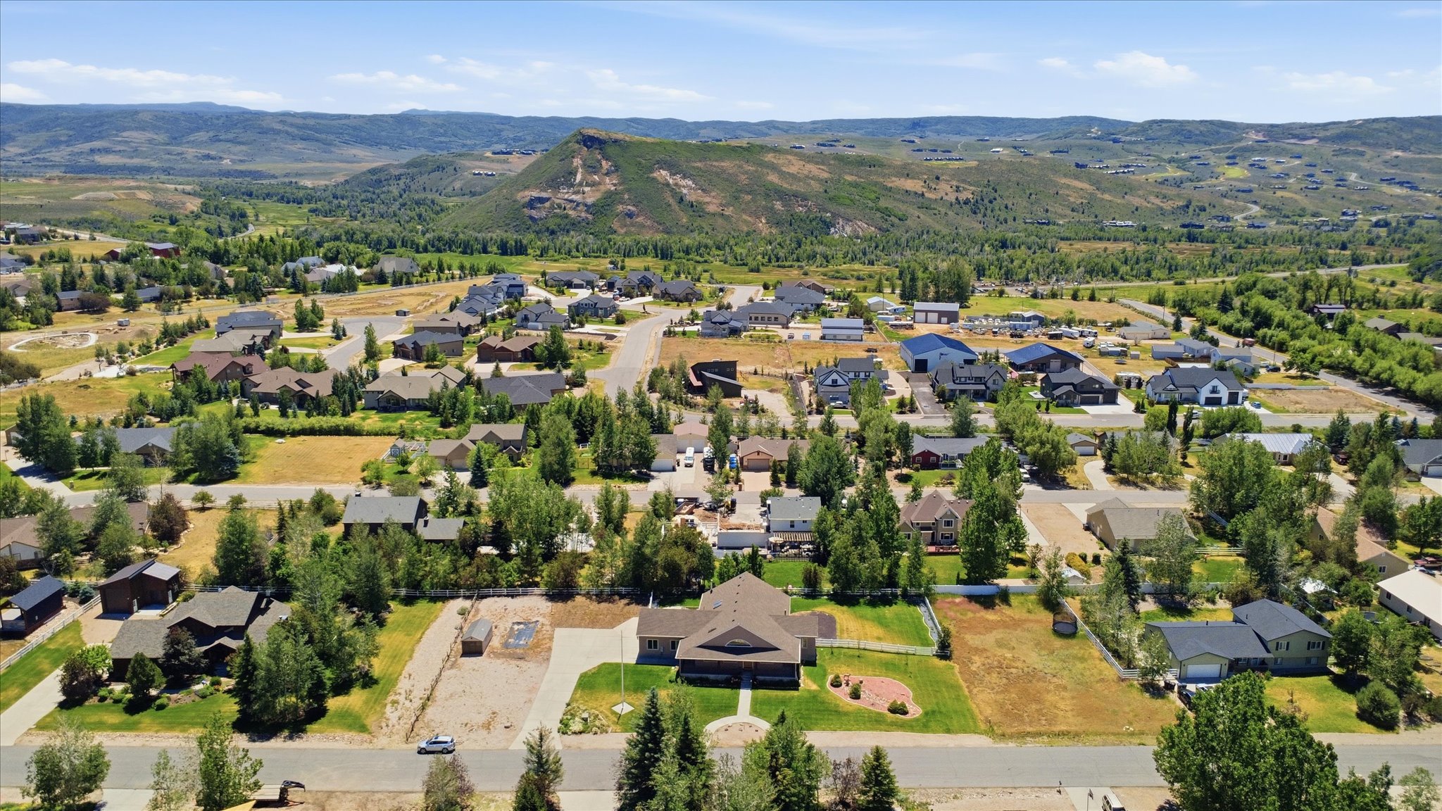 Expansive community featuring single-family residences, mature trees, paved streets, and a mountainous backdrop