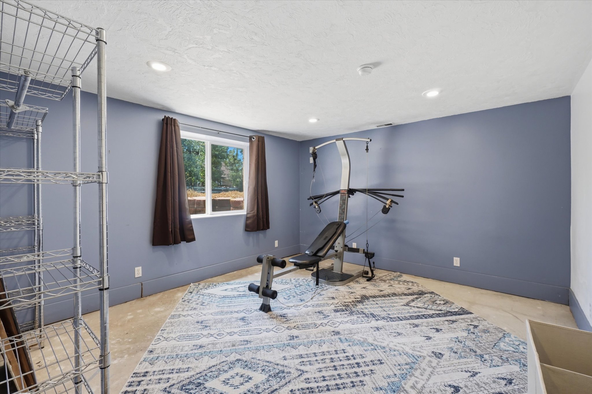 Flexible space featuring a window with exterior views, recessed lighting, and blue-painted walls