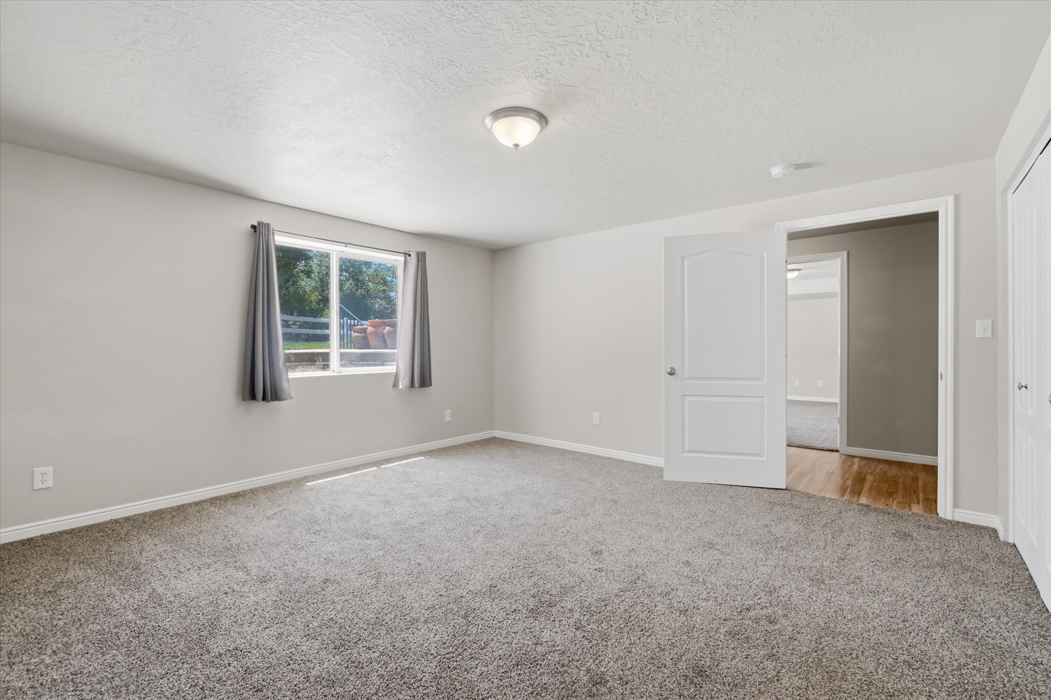 Carpeted room with a double-paned window, neutral wall paint, white trim, and a flush mount ceiling light