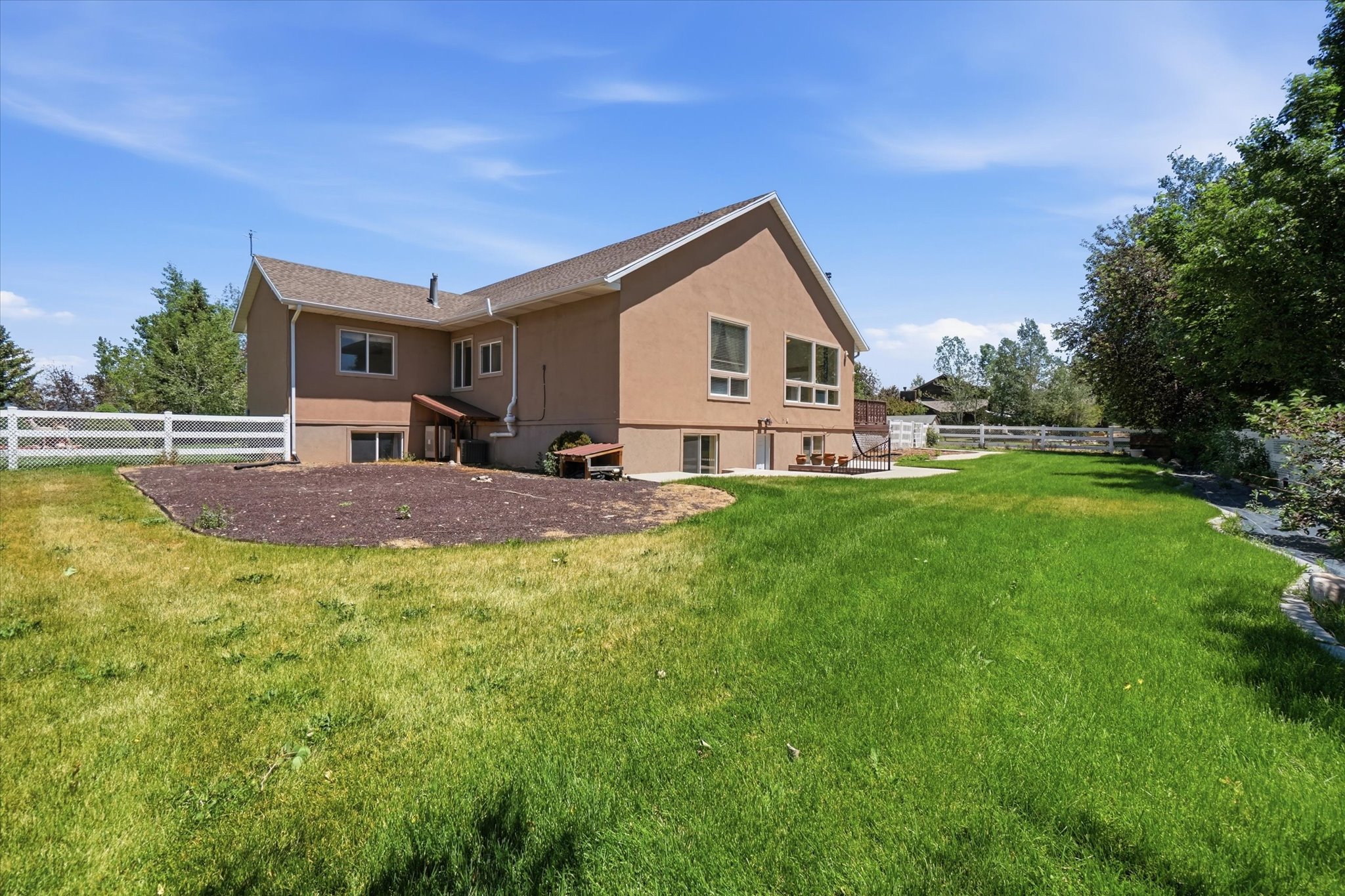 Expansive green lawn bordering a stucco-clad residence with multiple windows