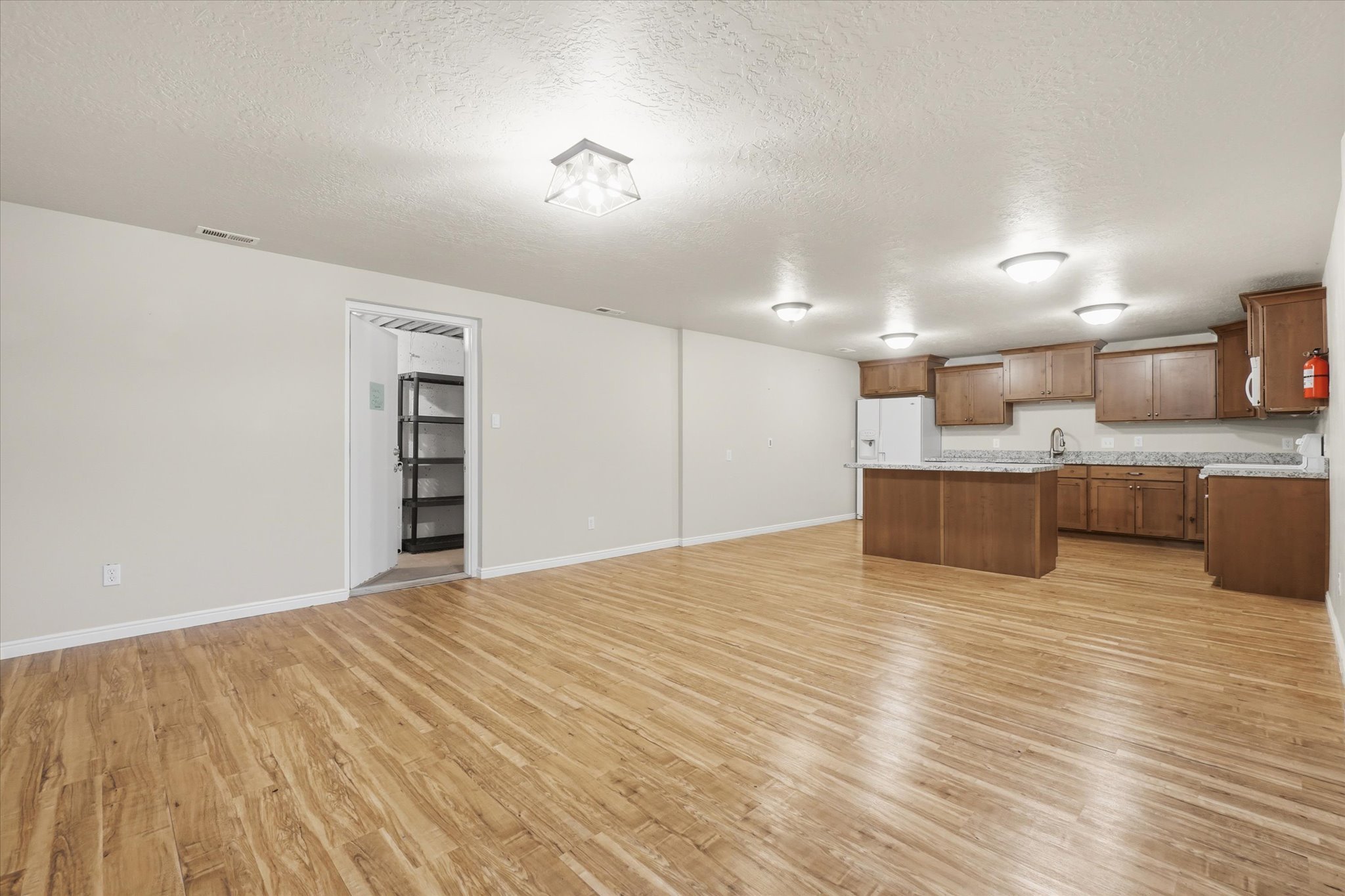 Open-concept living area featuring wood-finish flooring, recessed lighting, and a full kitchen