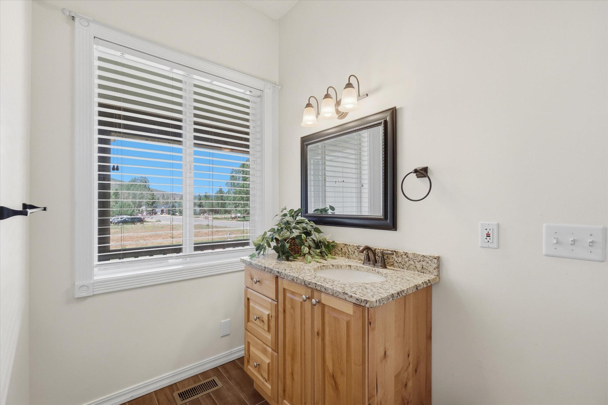 Bathroom vanity featuring a light wood cabinet, speckled countertop, and an oval undermount sink