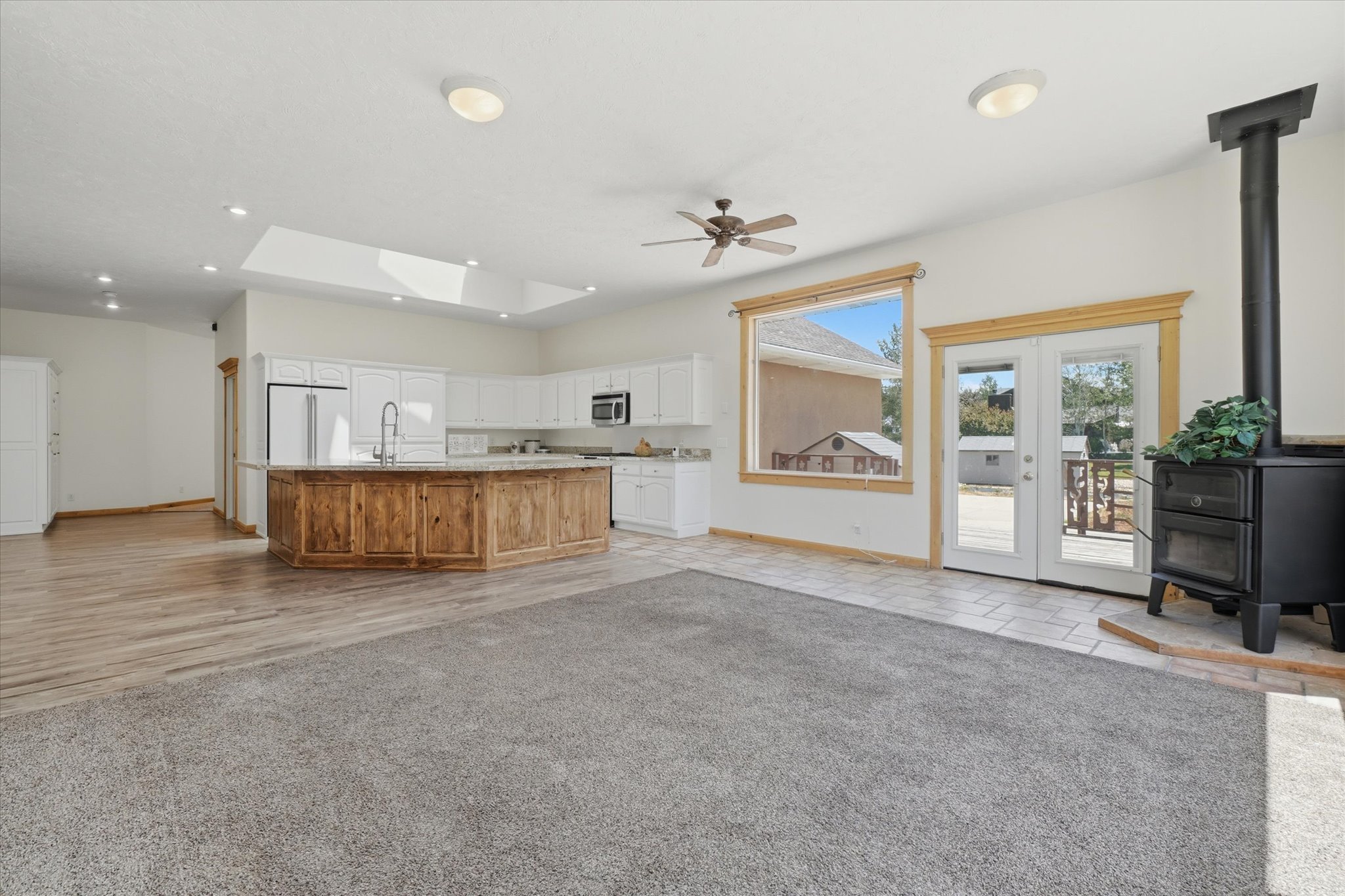 Spacious open-concept living area featuring a wood-finish kitchen island with stone countertop, white cabinetry, and stainless steel appliances