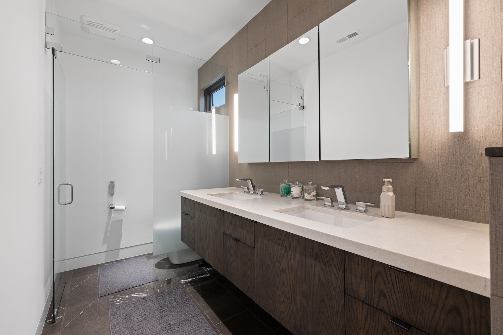 Contemporary bathroom featuring a double vanity with dark wood-finish cabinetry and light-toned countertops