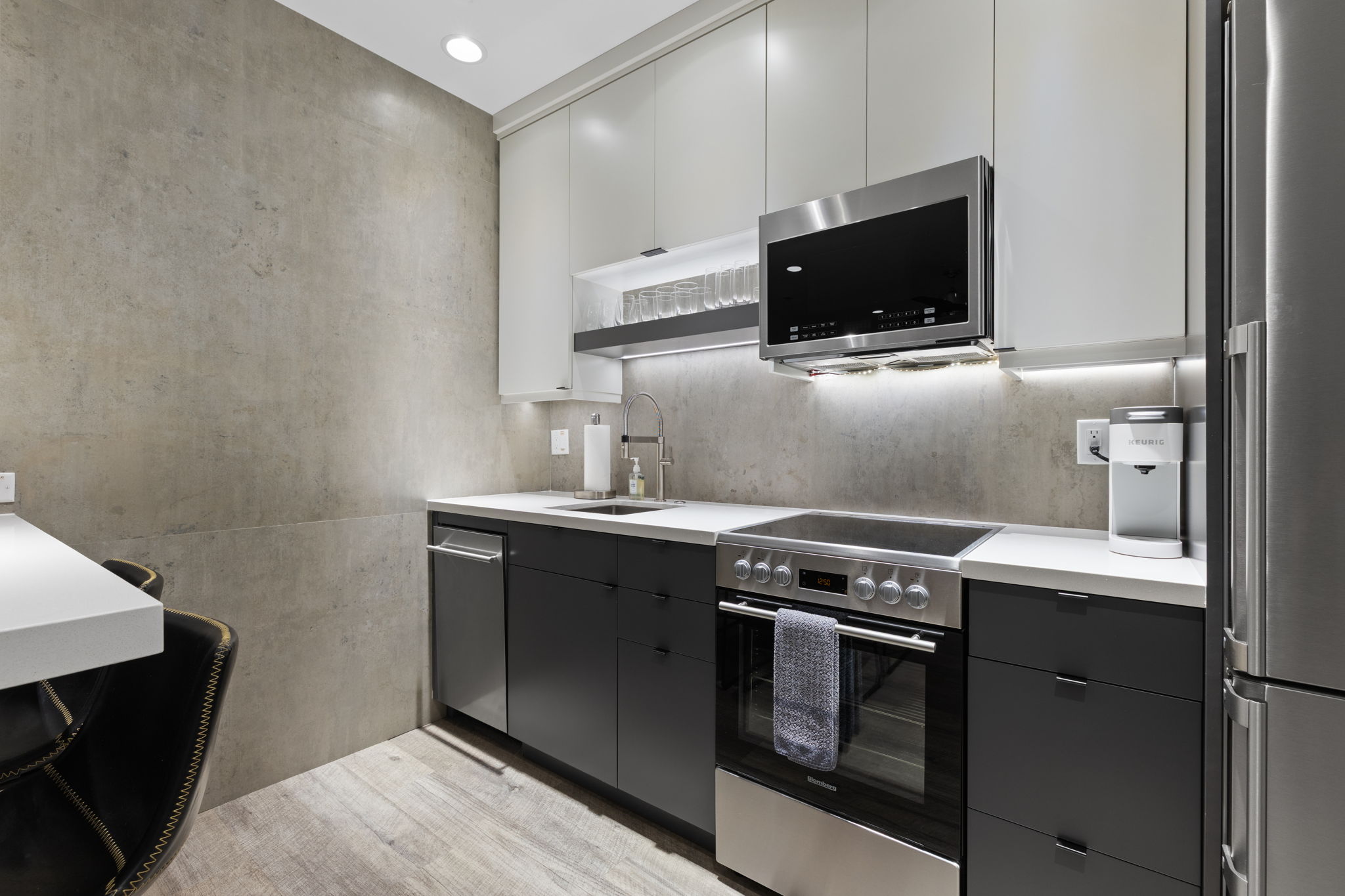 Modern kitchen featuring two-tone cabinetry, stainless steel appliances, and wood-finish flooring
