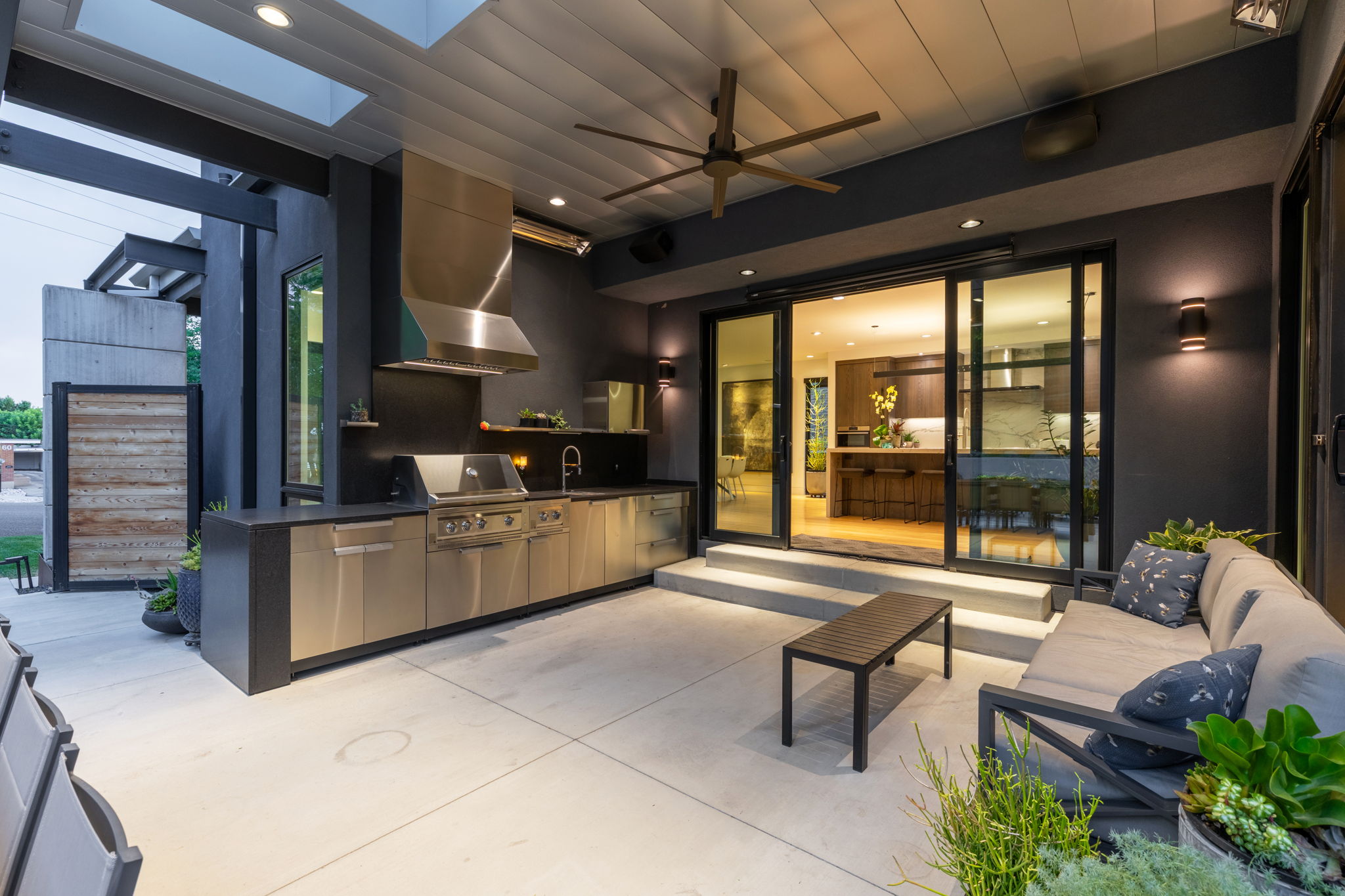 Expansive outdoor living area featuring a full stainless steel outdoor kitchen, built-in grill, and large range hood