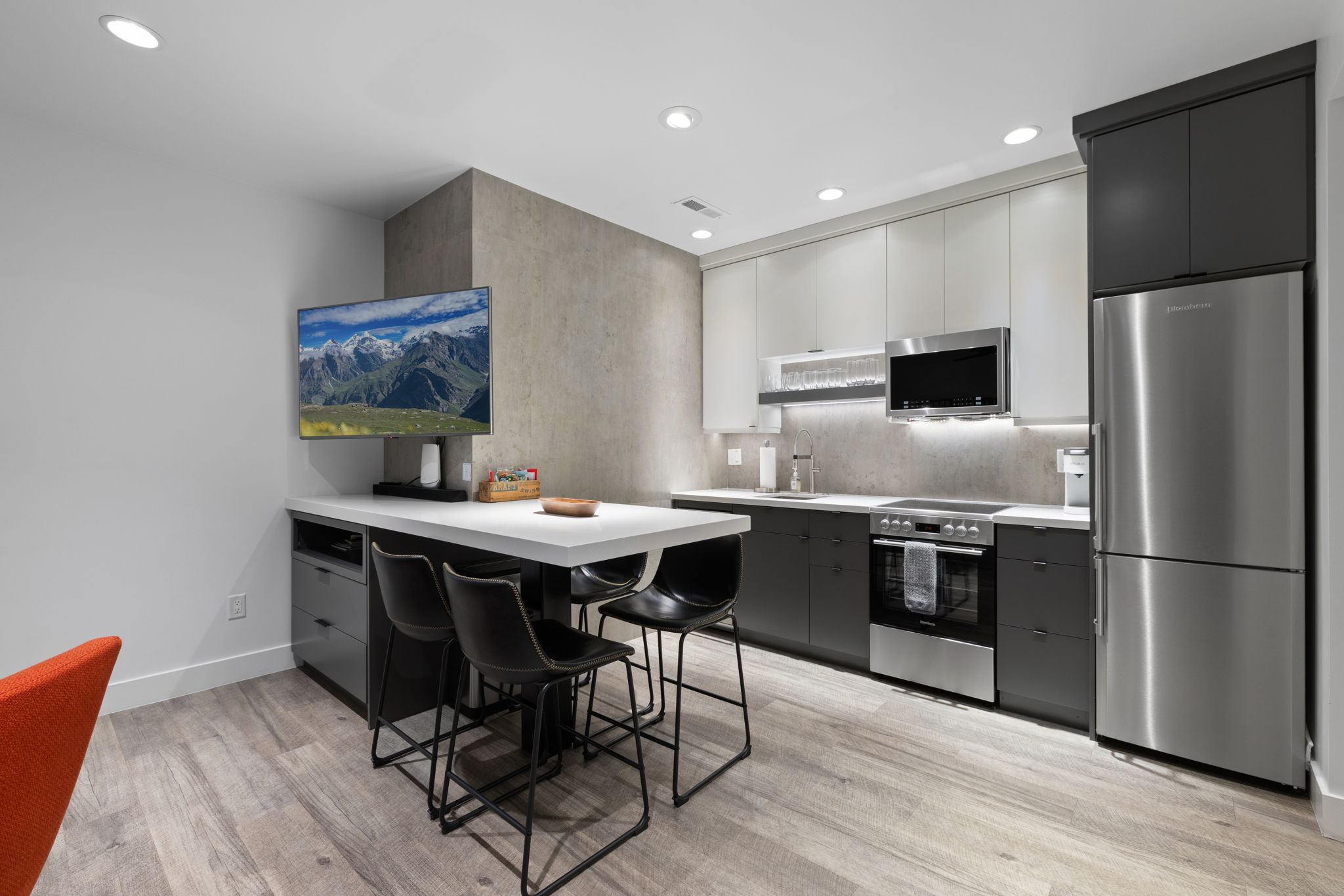 Contemporary kitchen featuring two-tone cabinetry, stainless steel appliances, recessed ceiling lighting, and wood-finish flooring