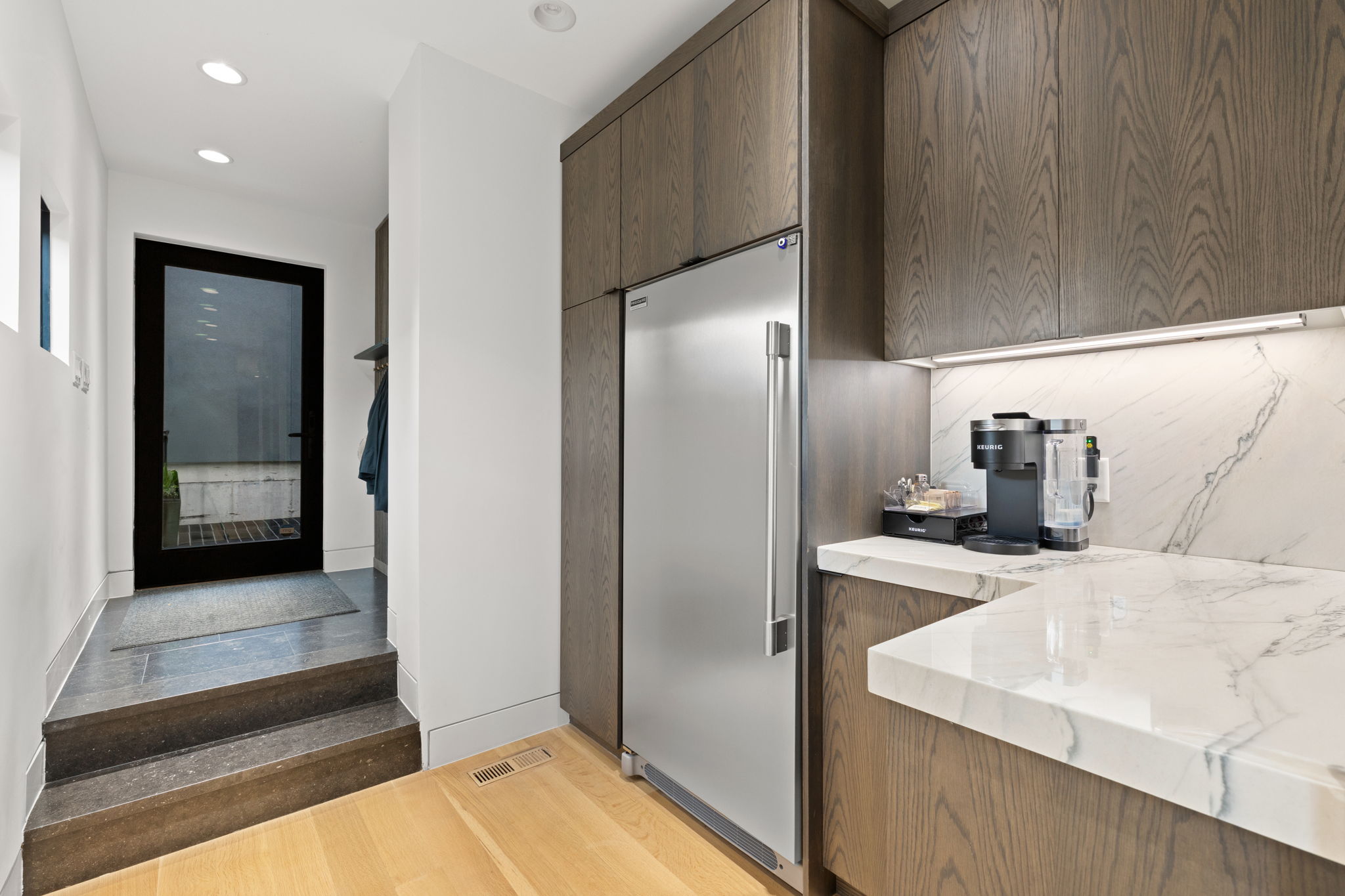 Contemporary kitchen featuring light wood-finish flooring and a stainless steel refrigerator