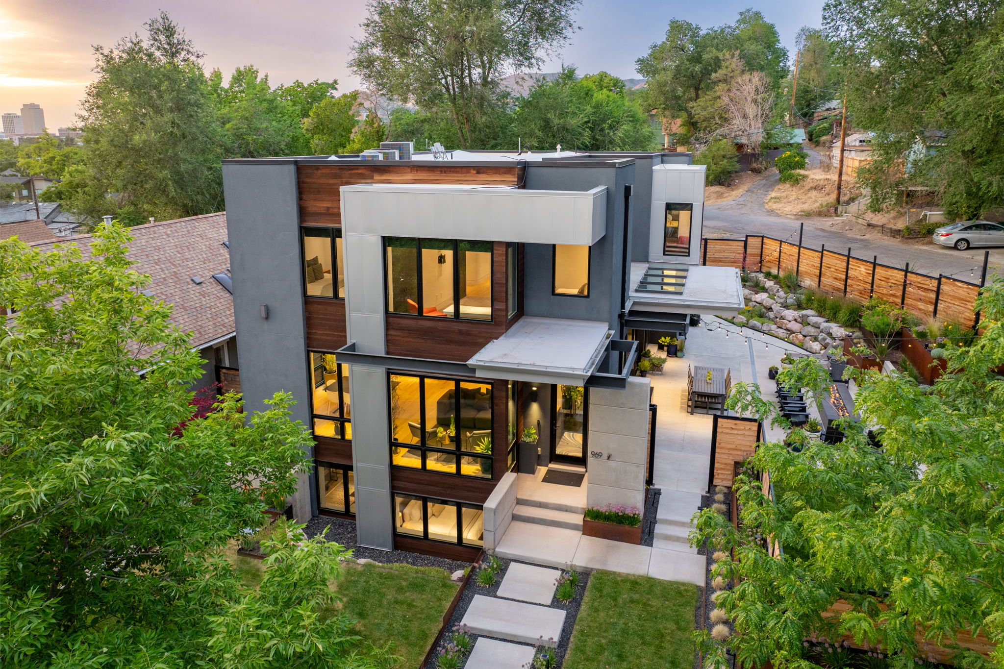 Contemporary multi-level residence featuring a flat roofline and a blend of gray stucco, white paneling, and wood-finish siding