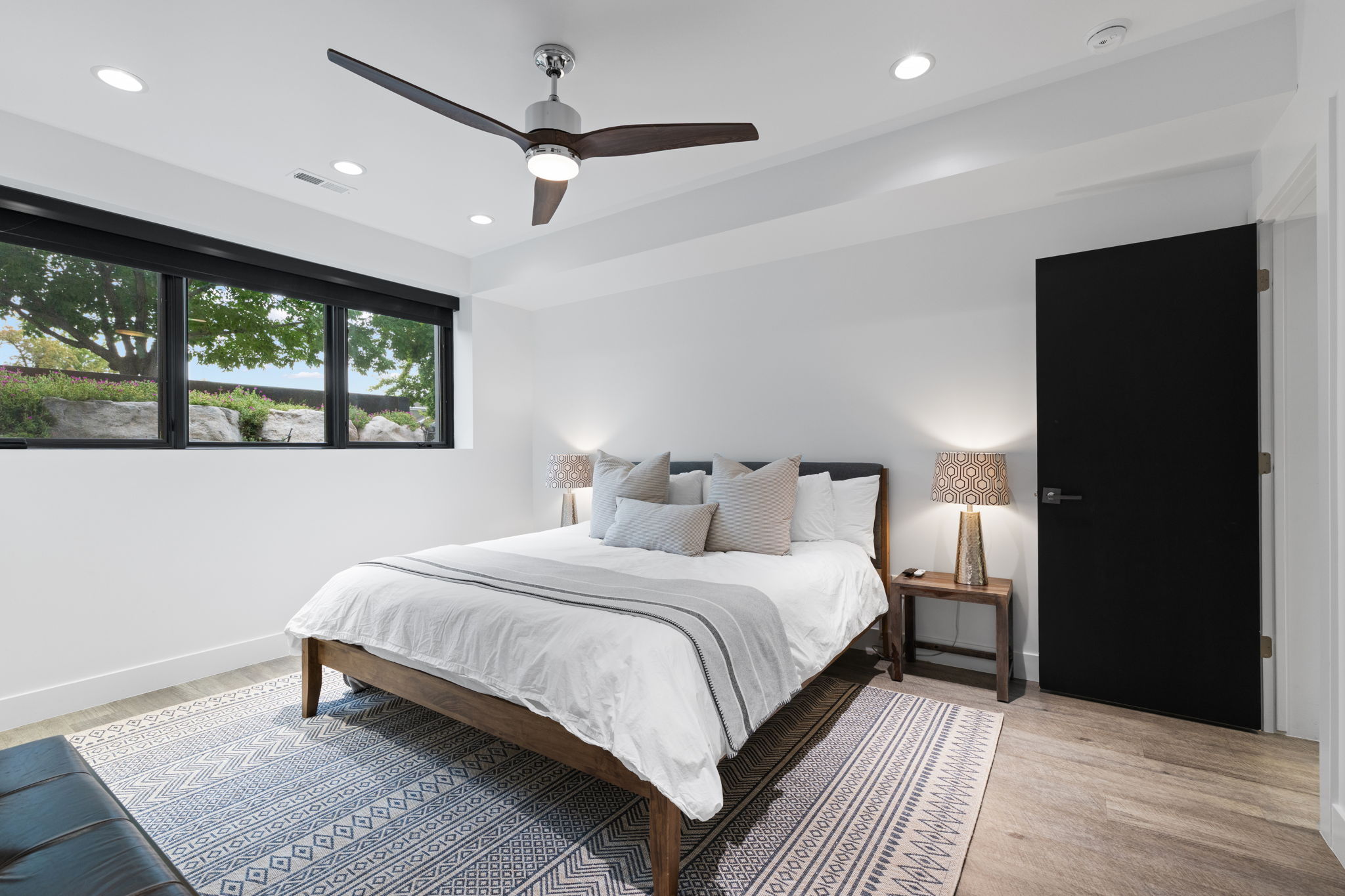 Spacious room featuring wood-finish flooring, a contemporary ceiling fan, recessed lighting, and a black interior door