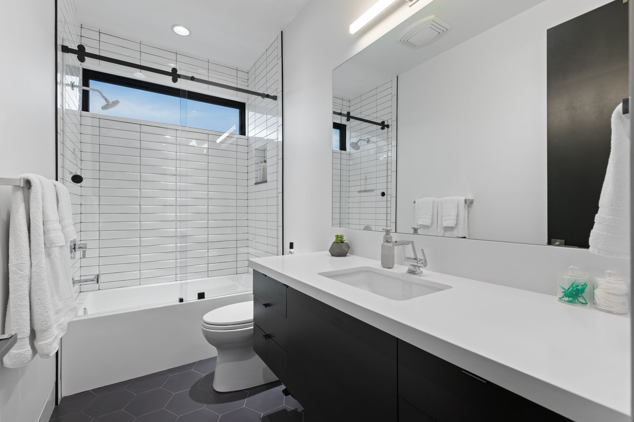 Contemporary bathroom featuring an integrated tub/shower with glass enclosure and subway tile surround