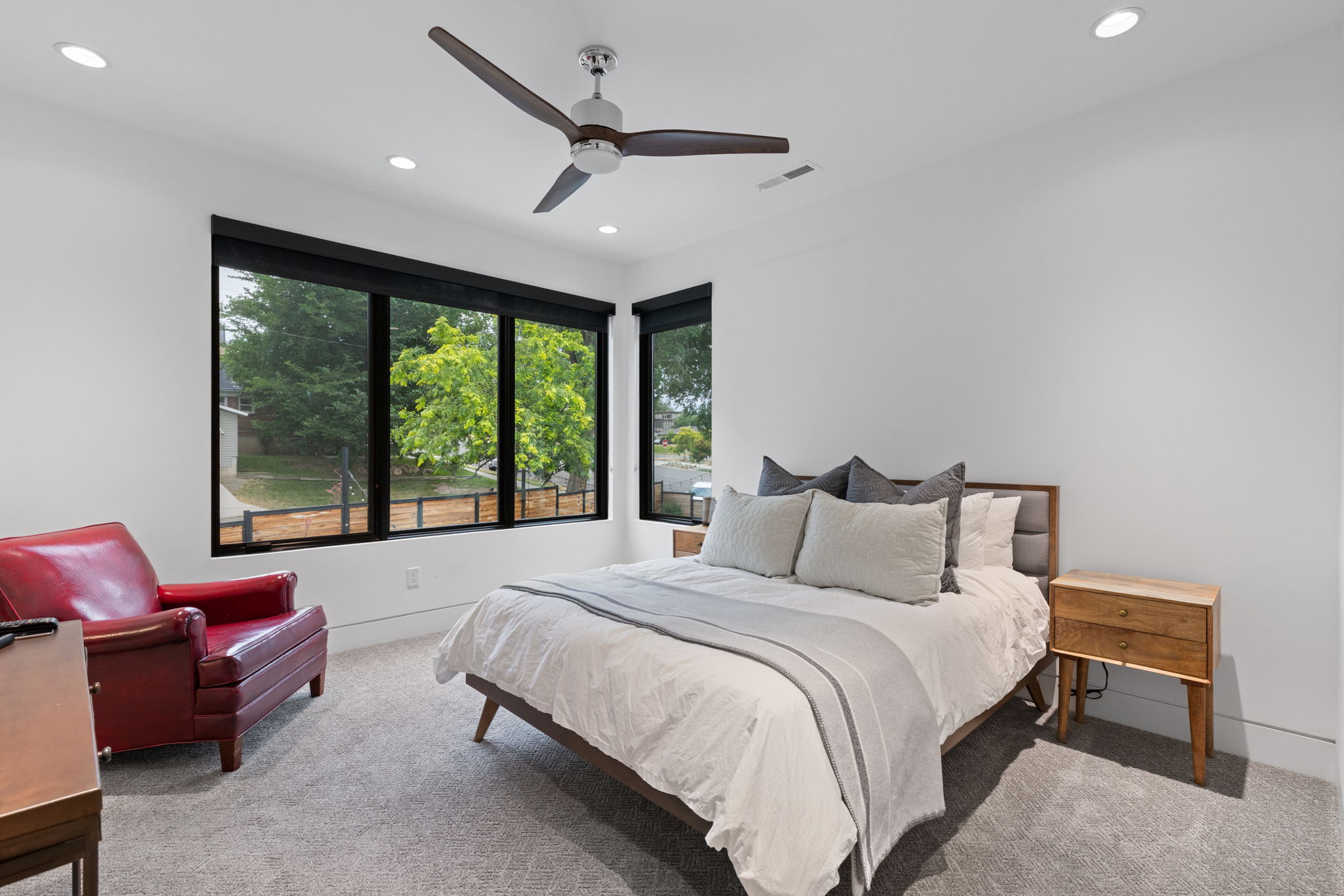 Spacious room featuring multiple large windows with black frames, recessed lighting, and a ceiling fan with wood-finish blades