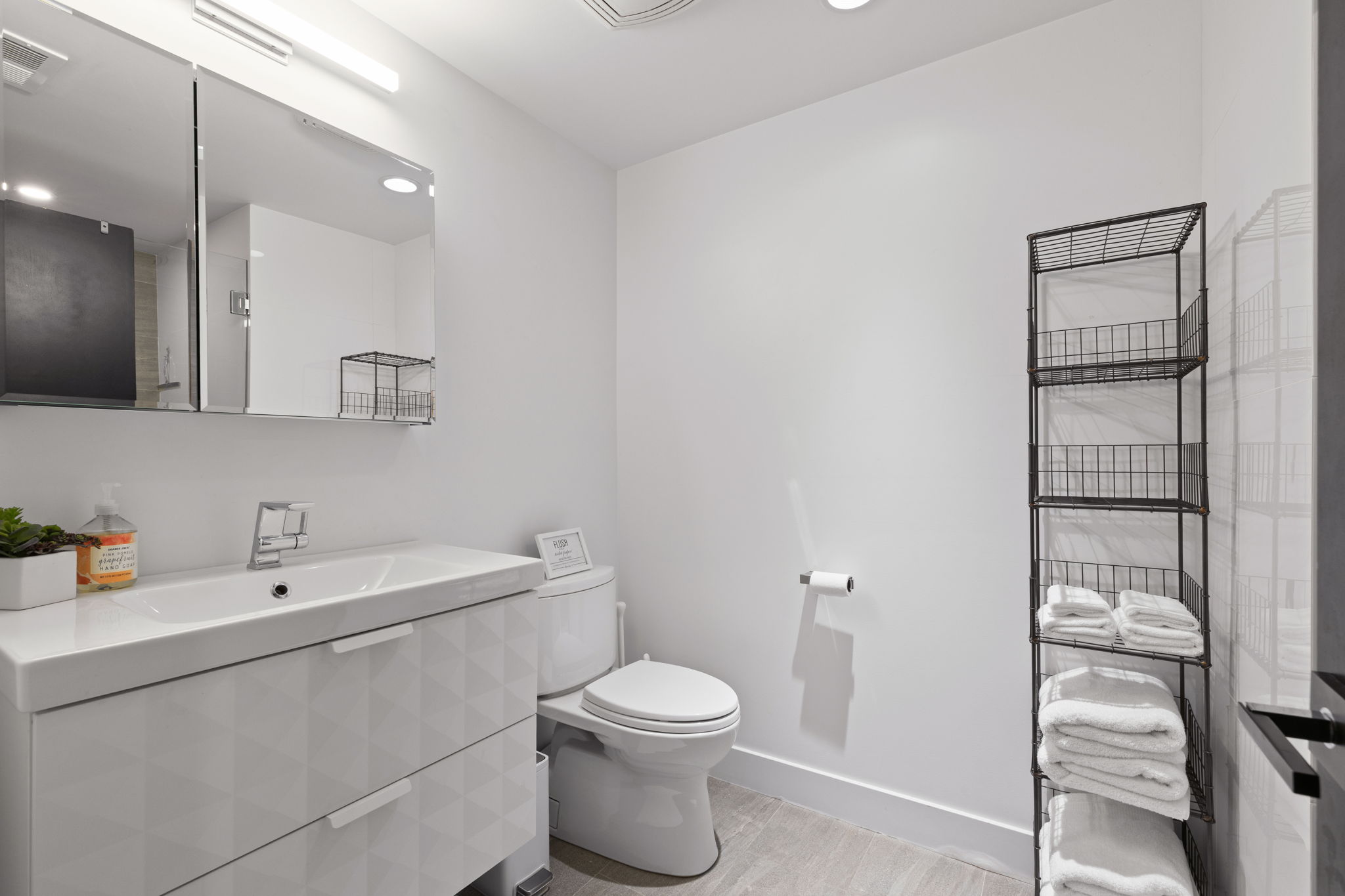 Contemporary bathroom featuring a white vanity with integrated sink, chrome faucet, and geometric-patterned drawers