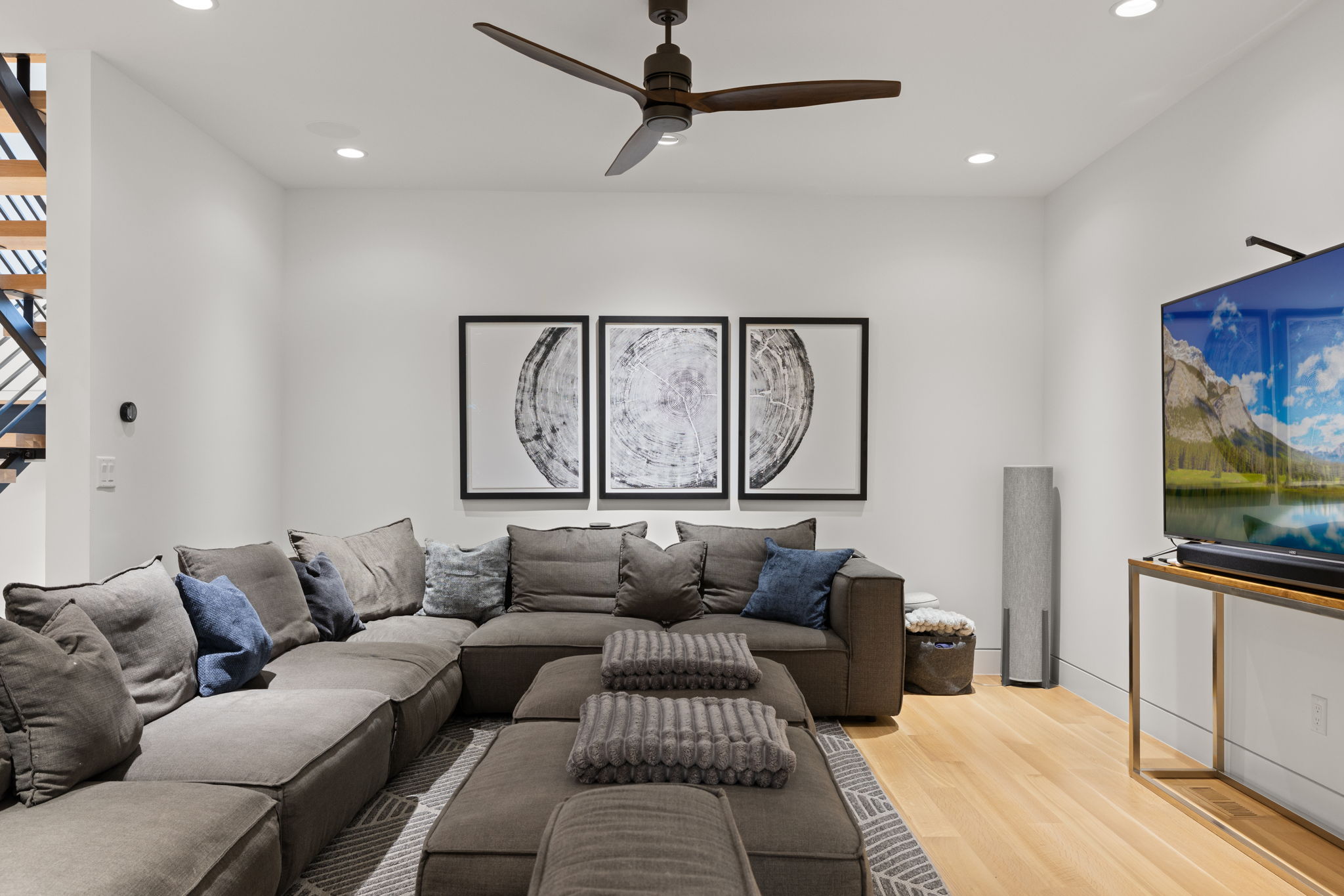 Spacious living area featuring light wood-finish flooring, recessed lighting, and a modern ceiling fan