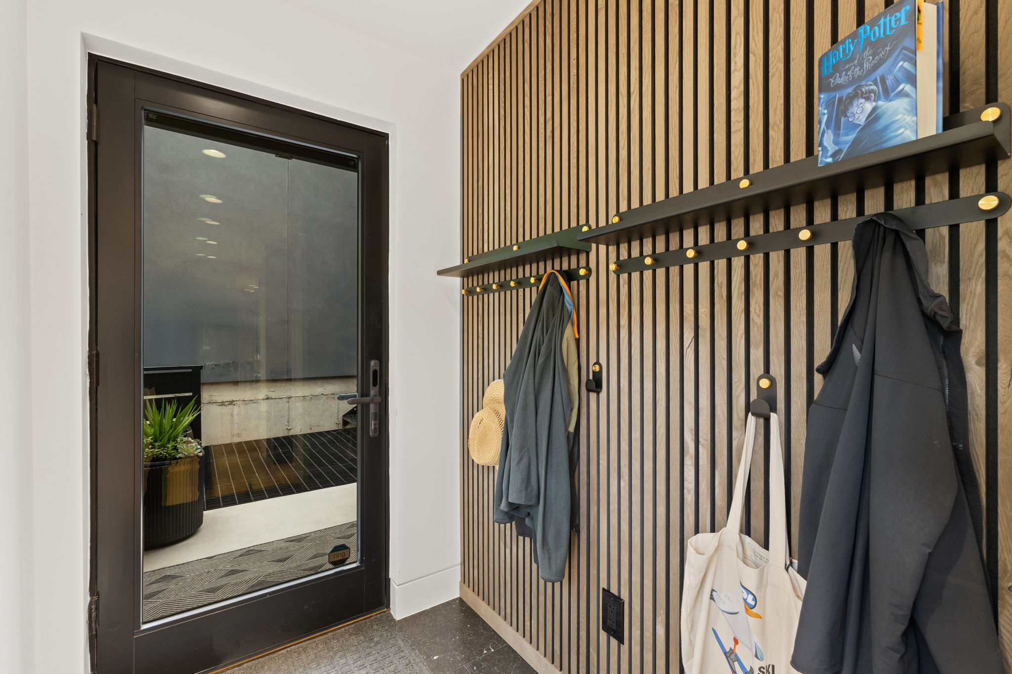 Entryway featuring a full-light door with black trim, a wood slat accent wall, and a built-in shelving system with integrated coat hooks
