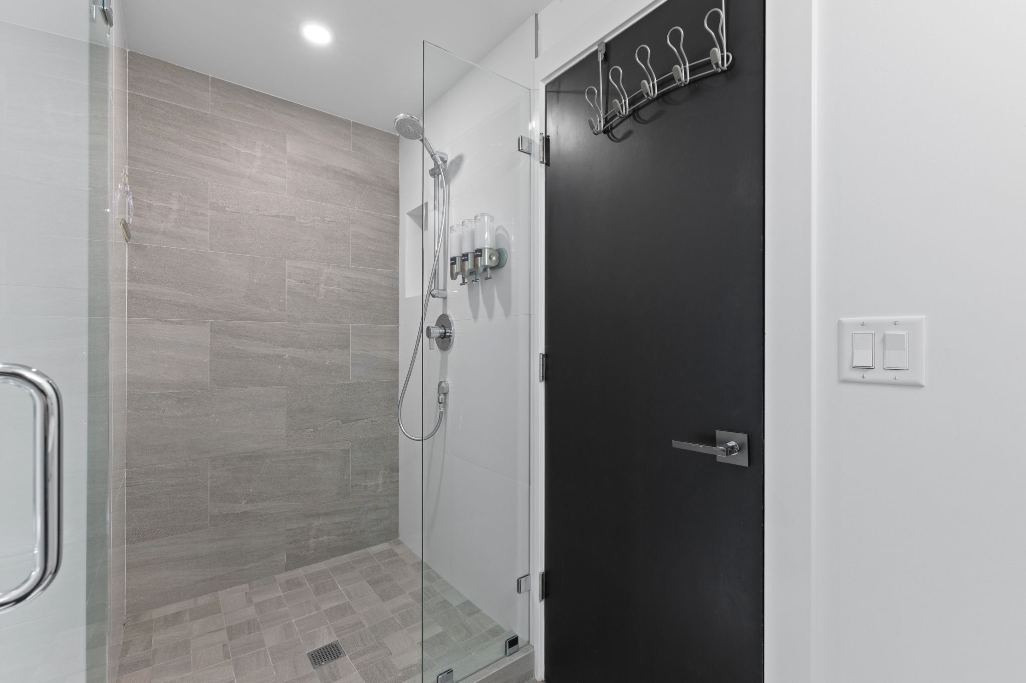 Contemporary shower enclosure featuring a glass panel, large format tile walls, and a tiled shower pan