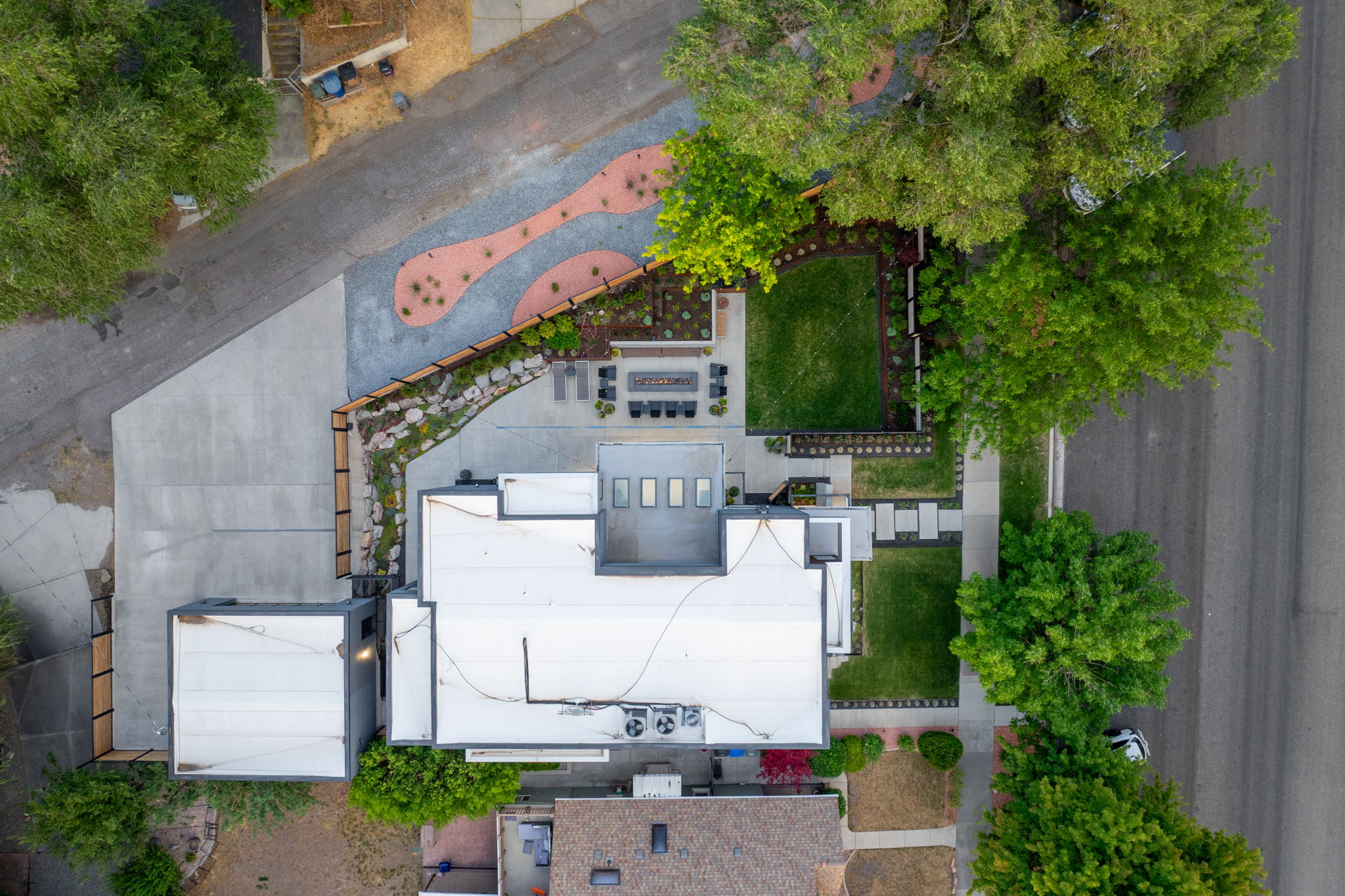 Extensive outdoor living spaces featuring a structured lawn area, a paver patio, a fire pit, and a gravel pathway with integrated landscaping