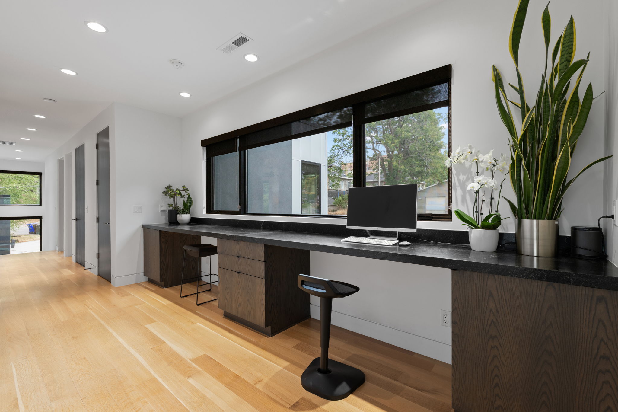 Integrated workspace featuring a dark stone countertop, built-in wood-finish cabinetry, and a large horizontal window