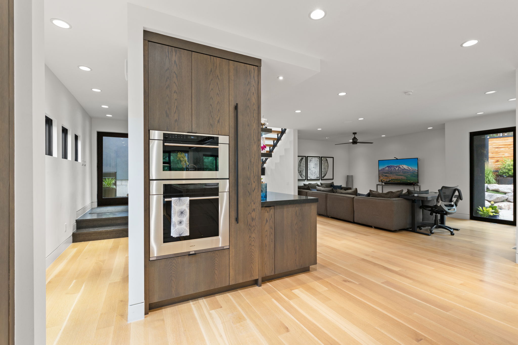 Integrated stainless steel double oven, wood-finish cabinetry, and dark stone countertop