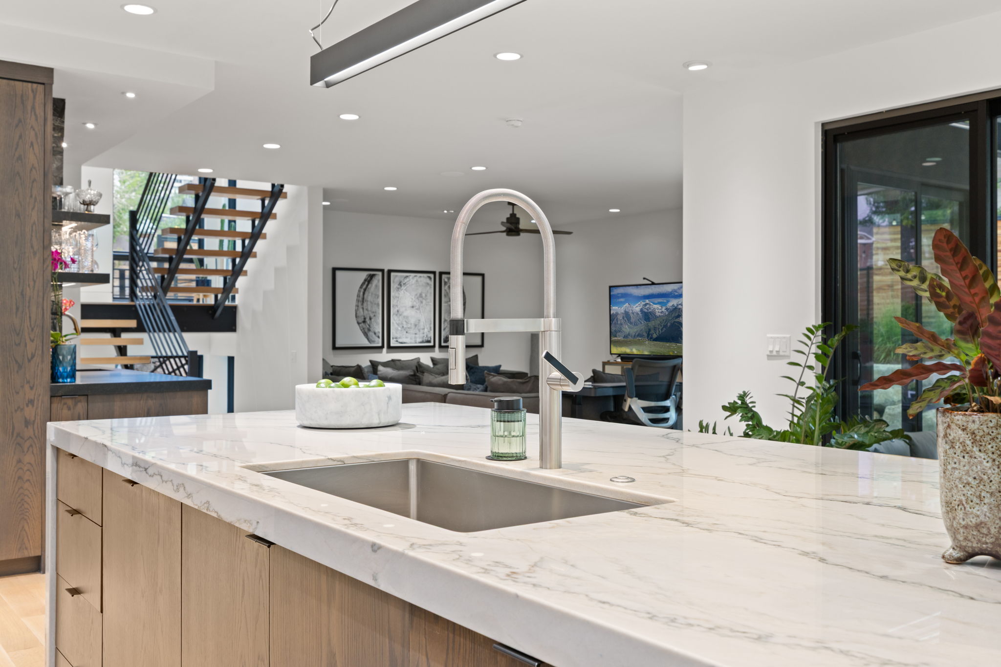 Kitchen island featuring a single-basin undermount sink with a gooseneck faucet, light-toned countertop, and wood-finish cabinetry