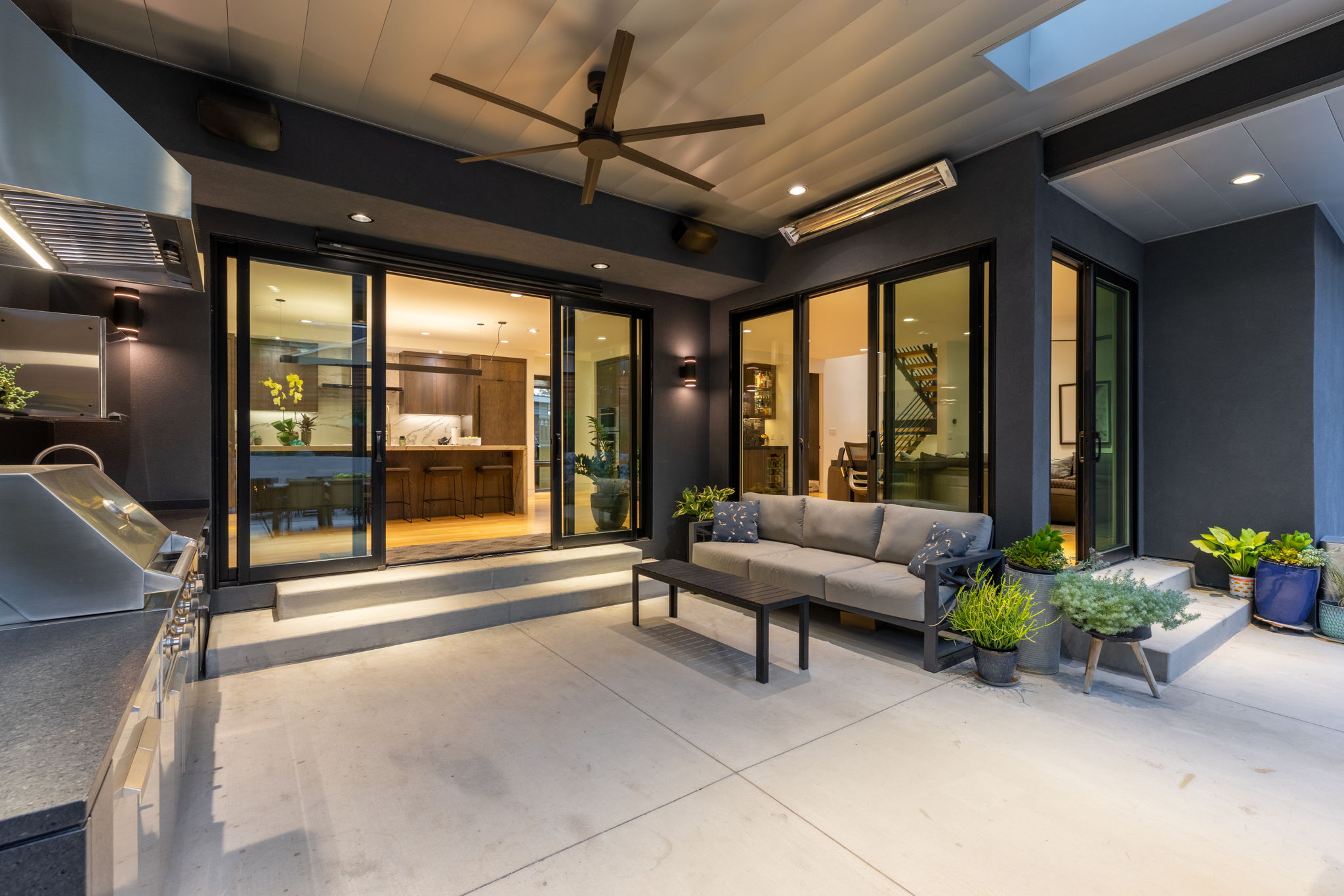 Spacious outdoor patio featuring a built-in grill station with dark countertop, an overhead exhaust hood, and recessed lighting