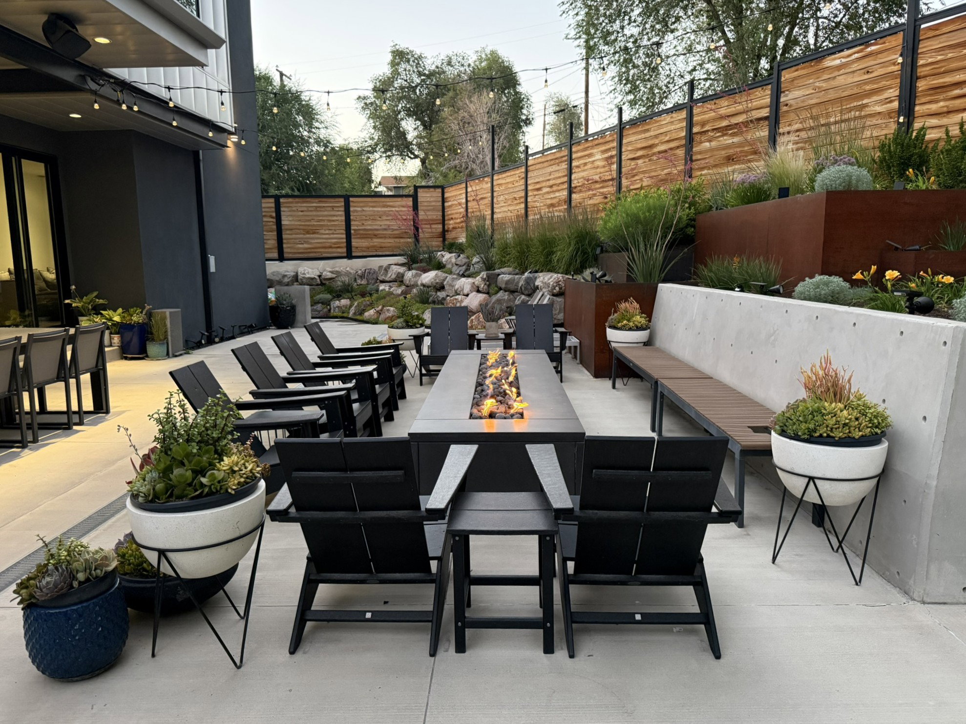Expansive patio featuring a fire pit, concrete benches, and a privacy fence