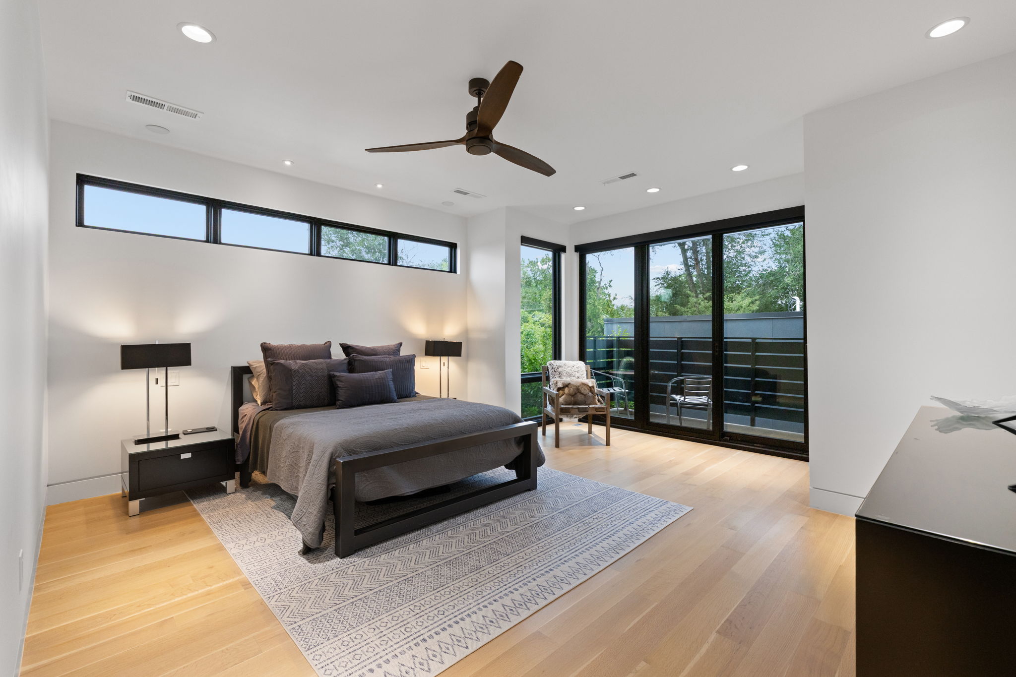 Spacious room featuring light wood-finish flooring, white walls, and a contemporary ceiling fan
