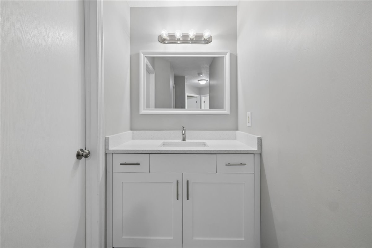 Bathroom vanity featuring a white shaker-style cabinet, integrated sink, and light-colored countertop