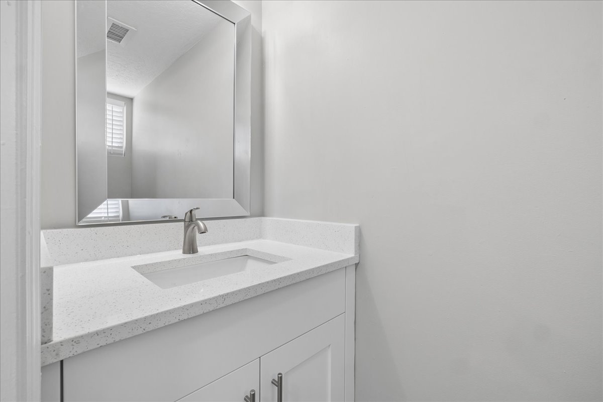 Bathroom vanity featuring a rectangular inset sink, brushed nickel faucet, and a light-toned countertop