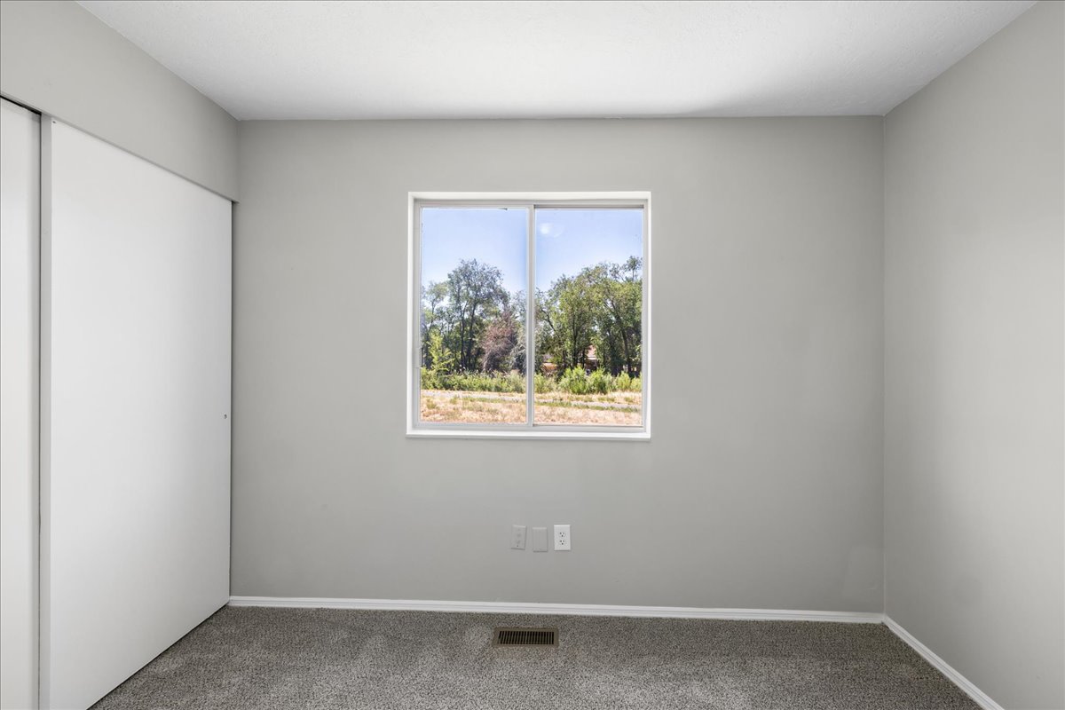 Interior room featuring neutral gray walls, a single-pane window with white trim, and a gray carpeted floor