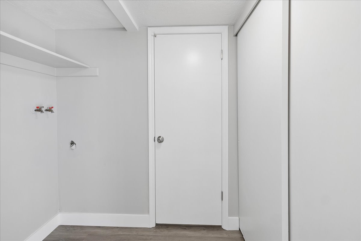 Utility area featuring wood-finish flooring, white walls, and built-in shelving