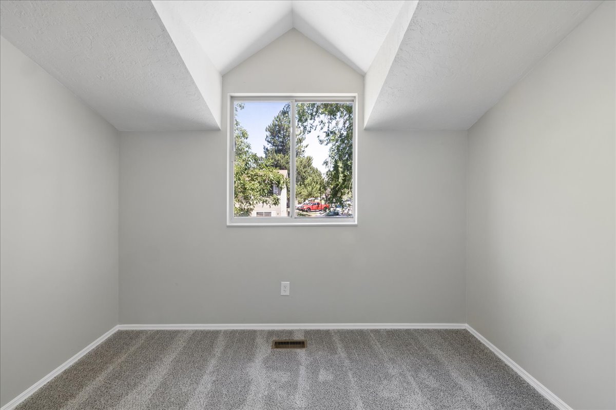 Room featuring a vaulted ceiling with exposed beams, light gray walls, and new gray carpet