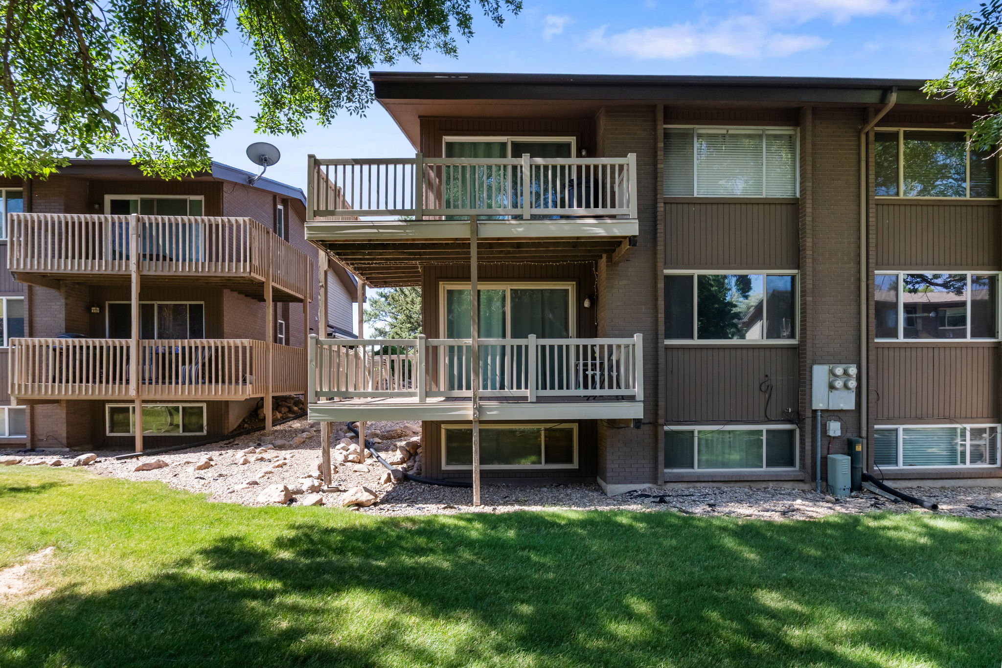 Multi-level residential building featuring wood-sided exterior and multiple private balconies with wood railings