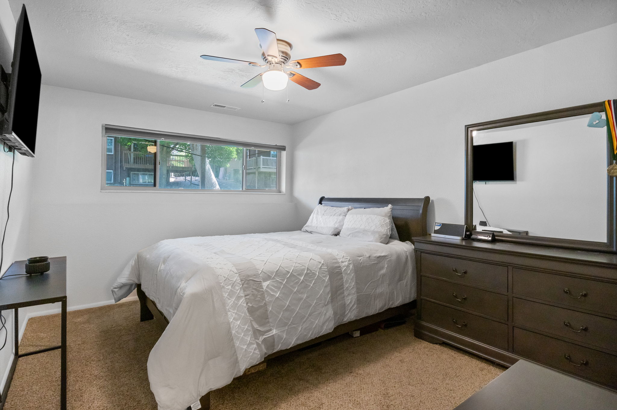 Carpeted room featuring a wide window, ceiling fan with light fixture, and white walls
