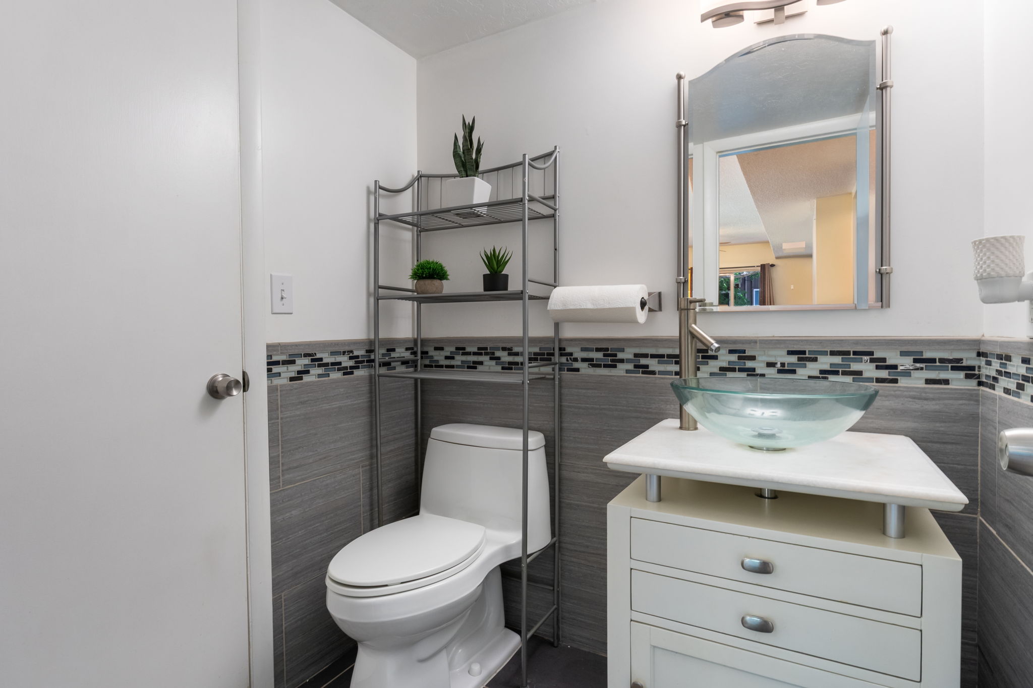 Bathroom featuring a modern vessel sink, white vanity with drawer storage, and a tile accent wall