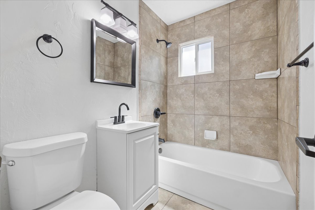 Bathroom featuring a white vanity with integrated sink, matte black hardware, and a framed mirror