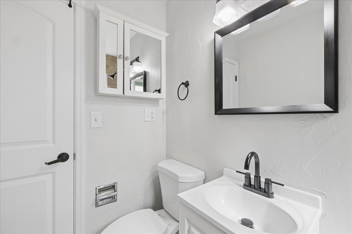 Bathroom featuring a white vanity with integrated sink, matte black faucet, and coordinating framed mirror with overhead lighting