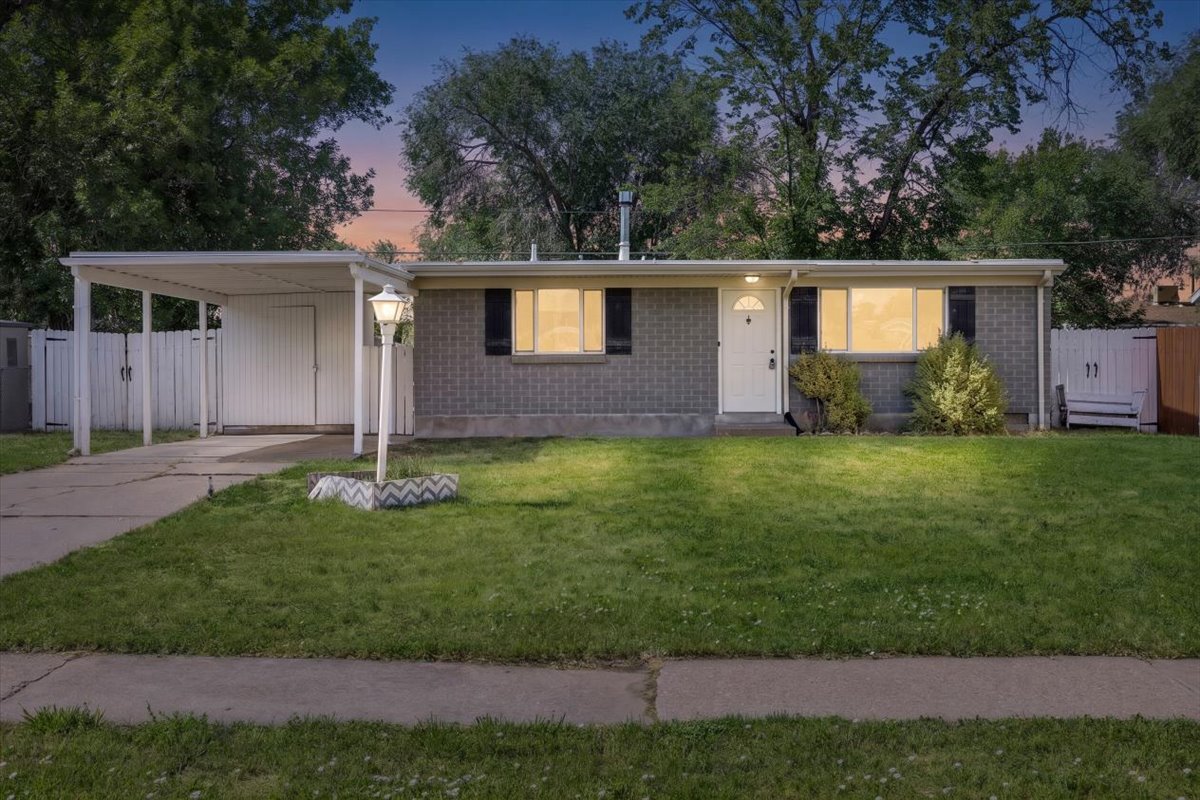 Single-story residence featuring a gray brick exterior, white front door, and a covered carport