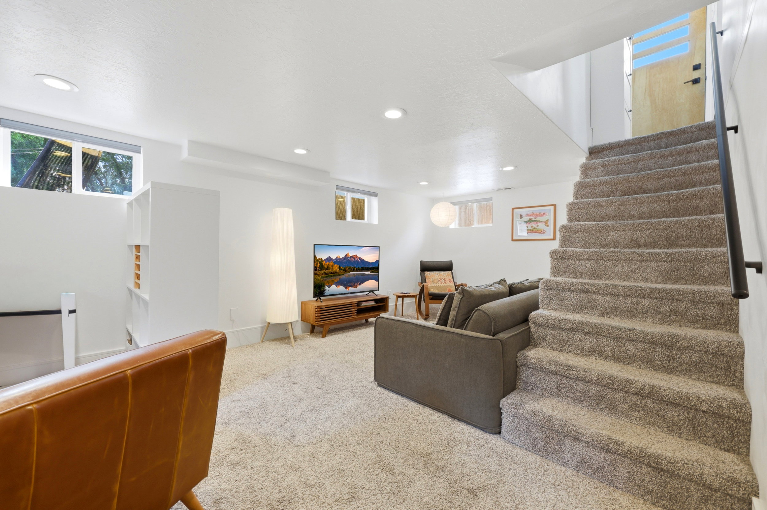 Carpeted staircase with a modern black handrail, leading to an upper level with a light wood-finish door