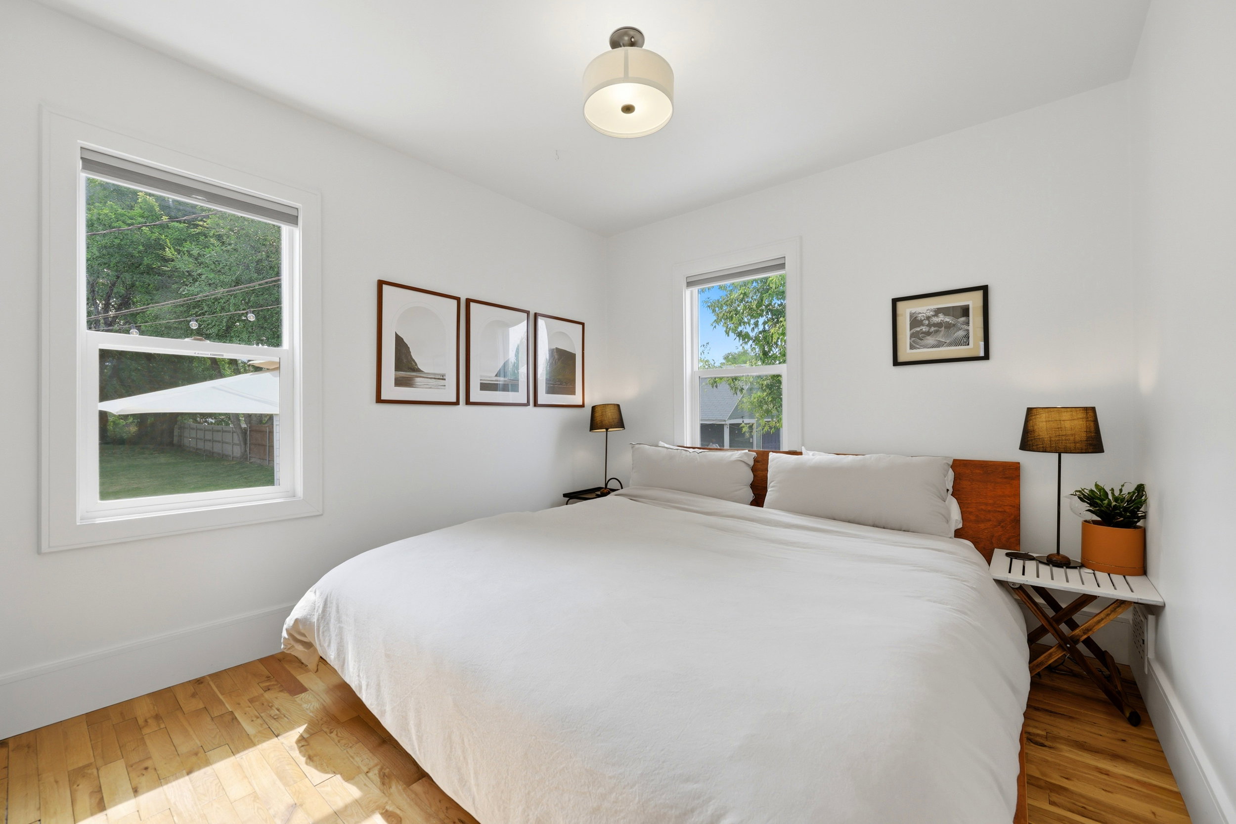 Bright bedroom featuring a built-in ceiling light fixture, wood-finish flooring, and white walls
