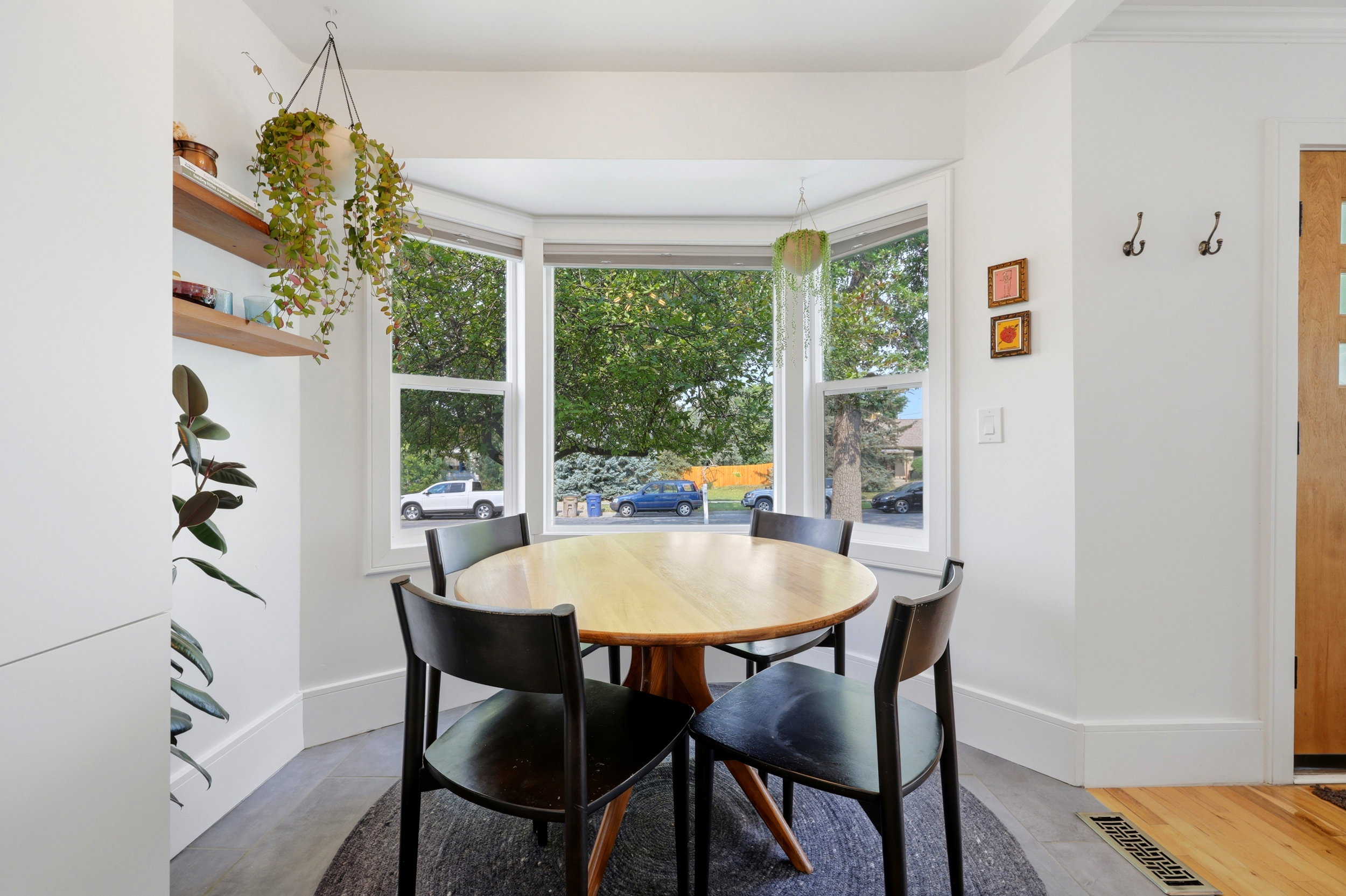 Dining nook featuring a bay window, wood-finish flooring, white baseboards, and built-in shelving