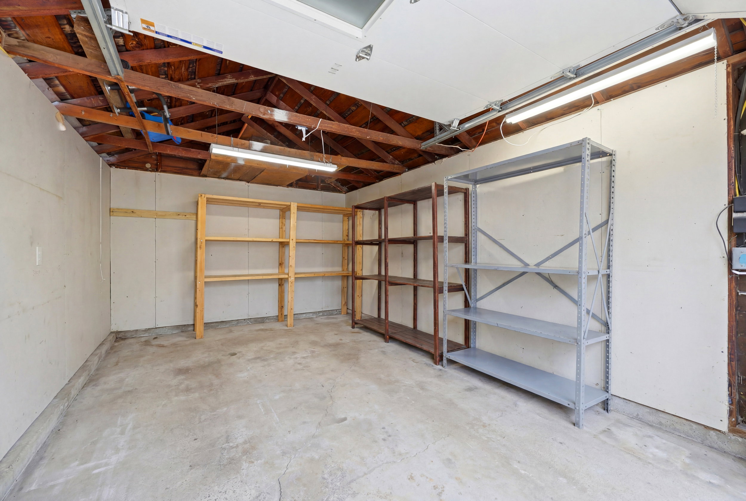 Garage space featuring exposed wood ceiling joists and concrete flooring