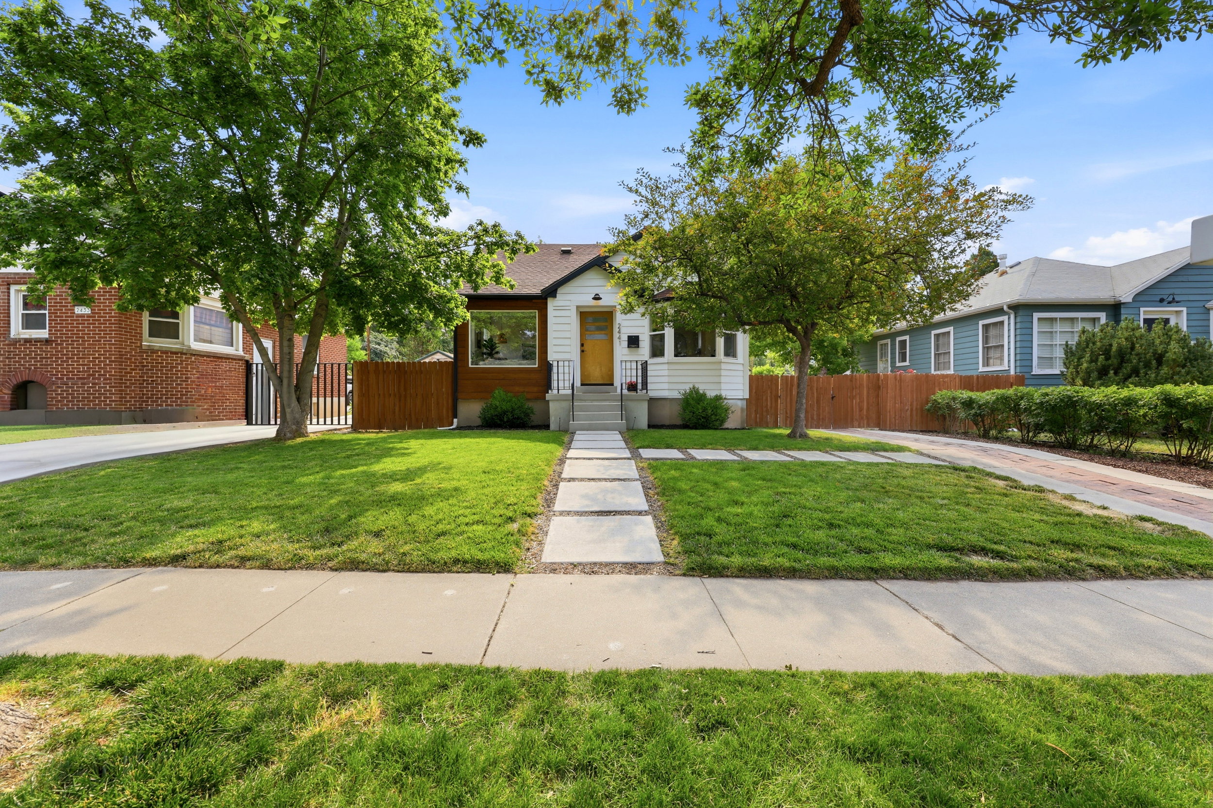 White exterior with wood siding accents, featuring a bright yellow front door