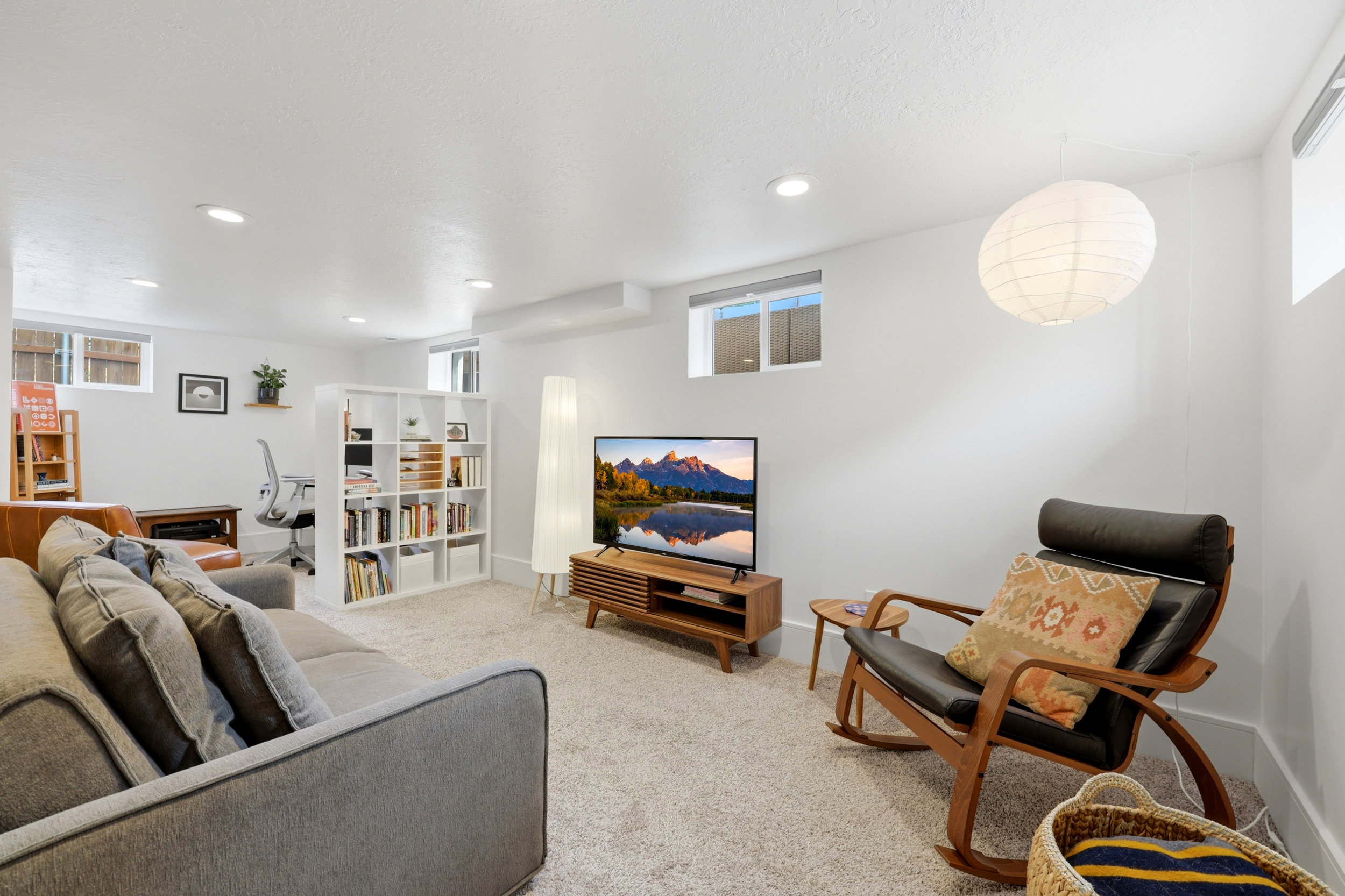Open-concept room featuring light-colored carpeting, multiple recessed ceiling lights, and two windows providing natural light