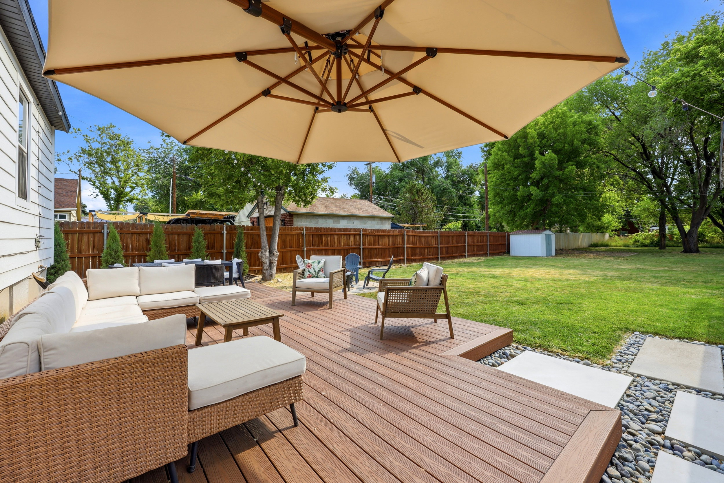 Expansive backyard featuring a multi-level composite deck, mature trees, a manicured lawn, and a privacy fence