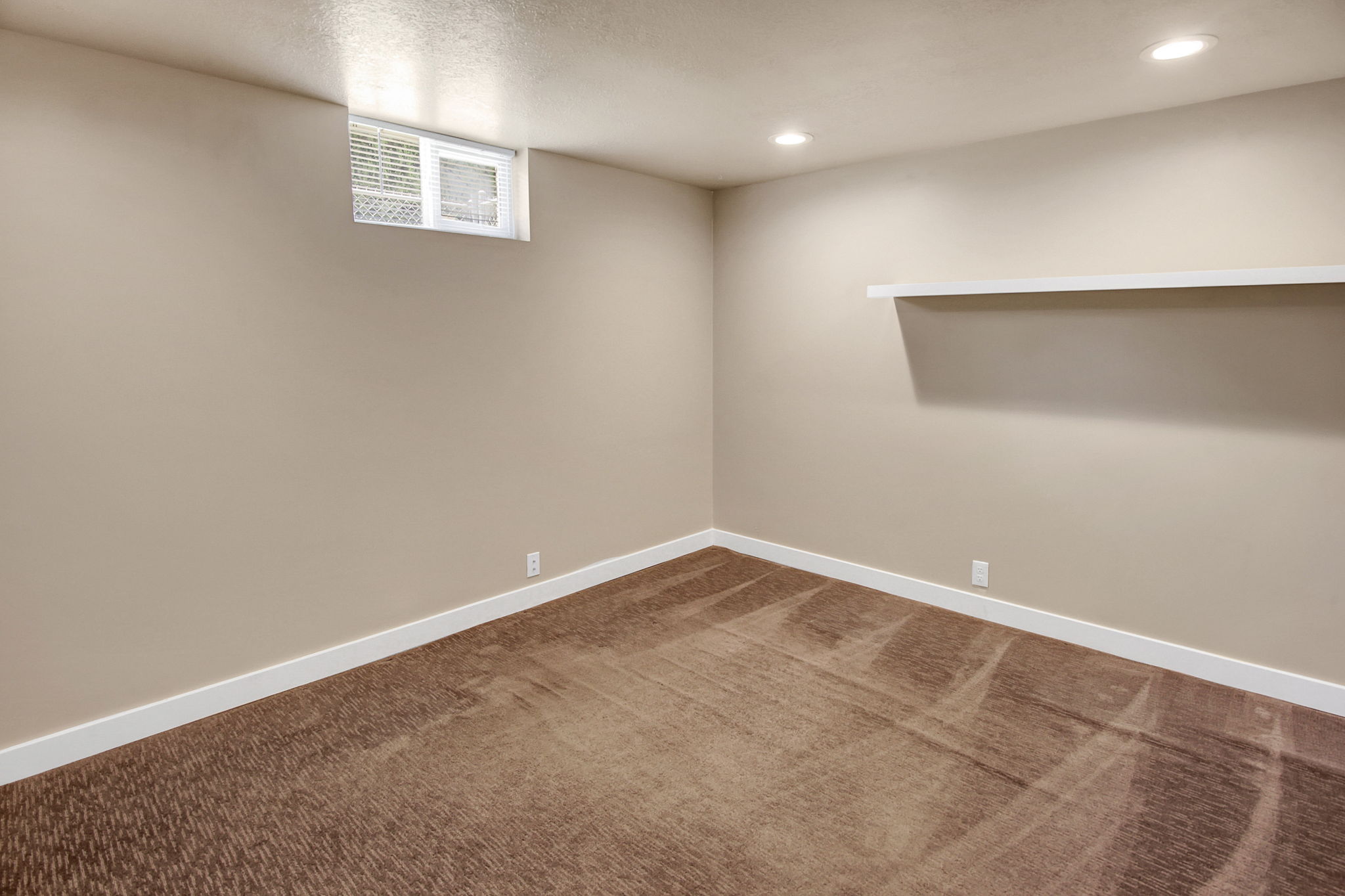 Carpeted room featuring a white baseboard trim, neutral wall paint, recessed lighting, a built-in floating shelf, and a horizontal window with blinds