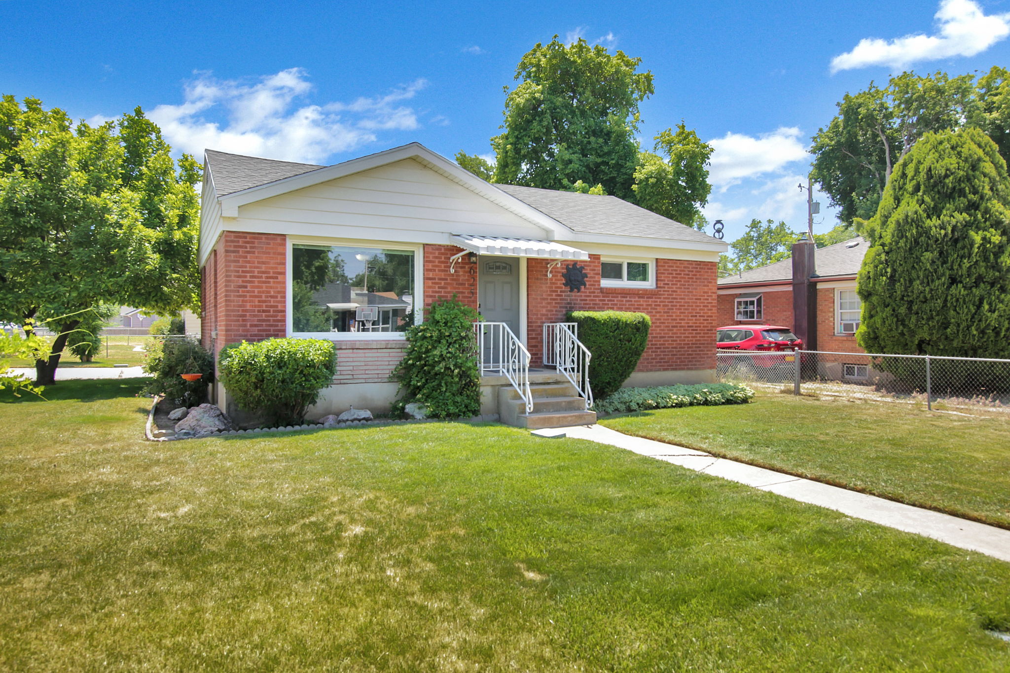 Brick ranch-style residence featuring a prominent front lawn and a concrete walkway leading to the entrance