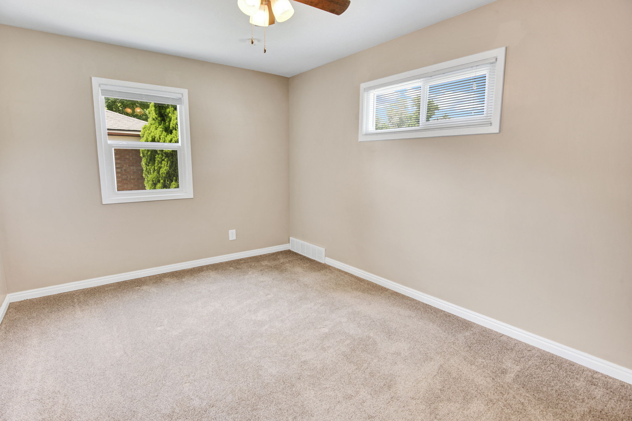 Neutral-toned walls and plush carpeting complement the natural light provided by two windows